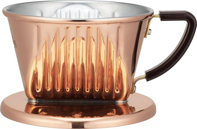 Copper KALITA coffee dripper with three-hole design, featuring a conical shape, ribbed interior, and dark handle. Polished copper exterior reflects warm light, highlighting its handcrafted quality and heat-conducting properties for optimal coffee extraction.