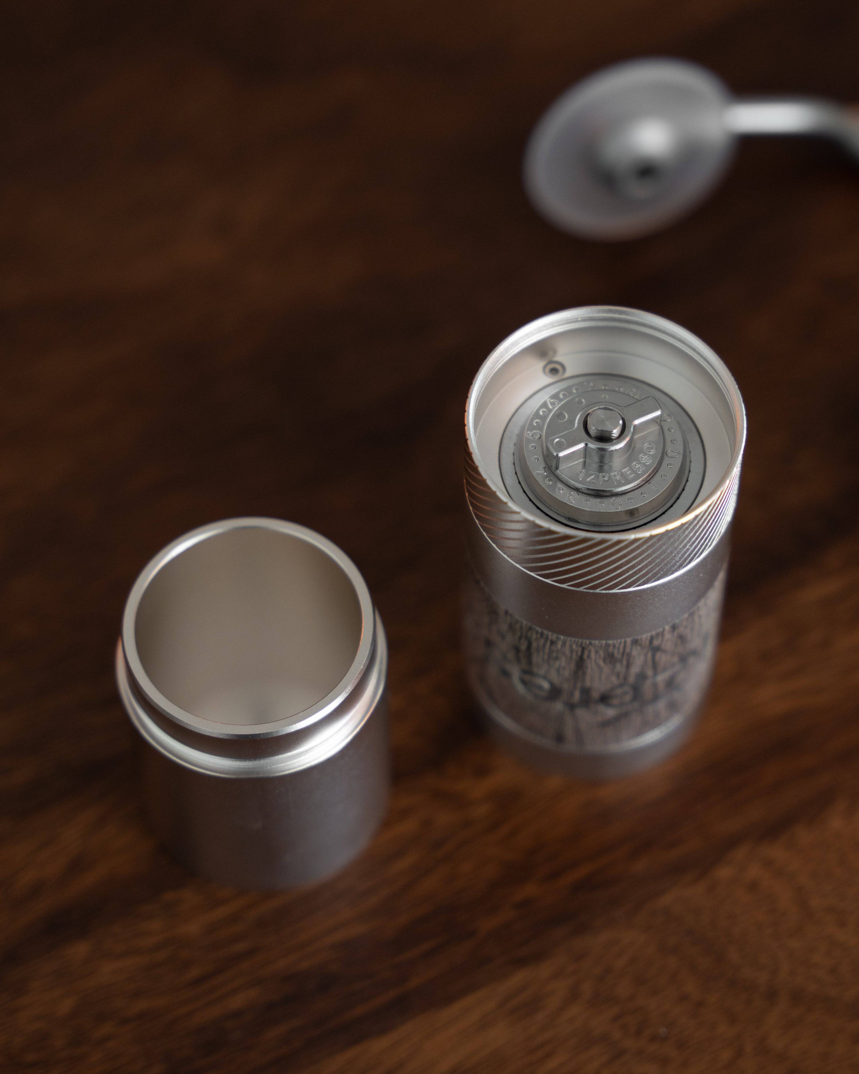 1Zpresso QS2 manual coffee grinder disassembled on wooden surface, showcasing compact design, stainless steel body, and precision grinding mechanism for portable, high-quality coffee grinding