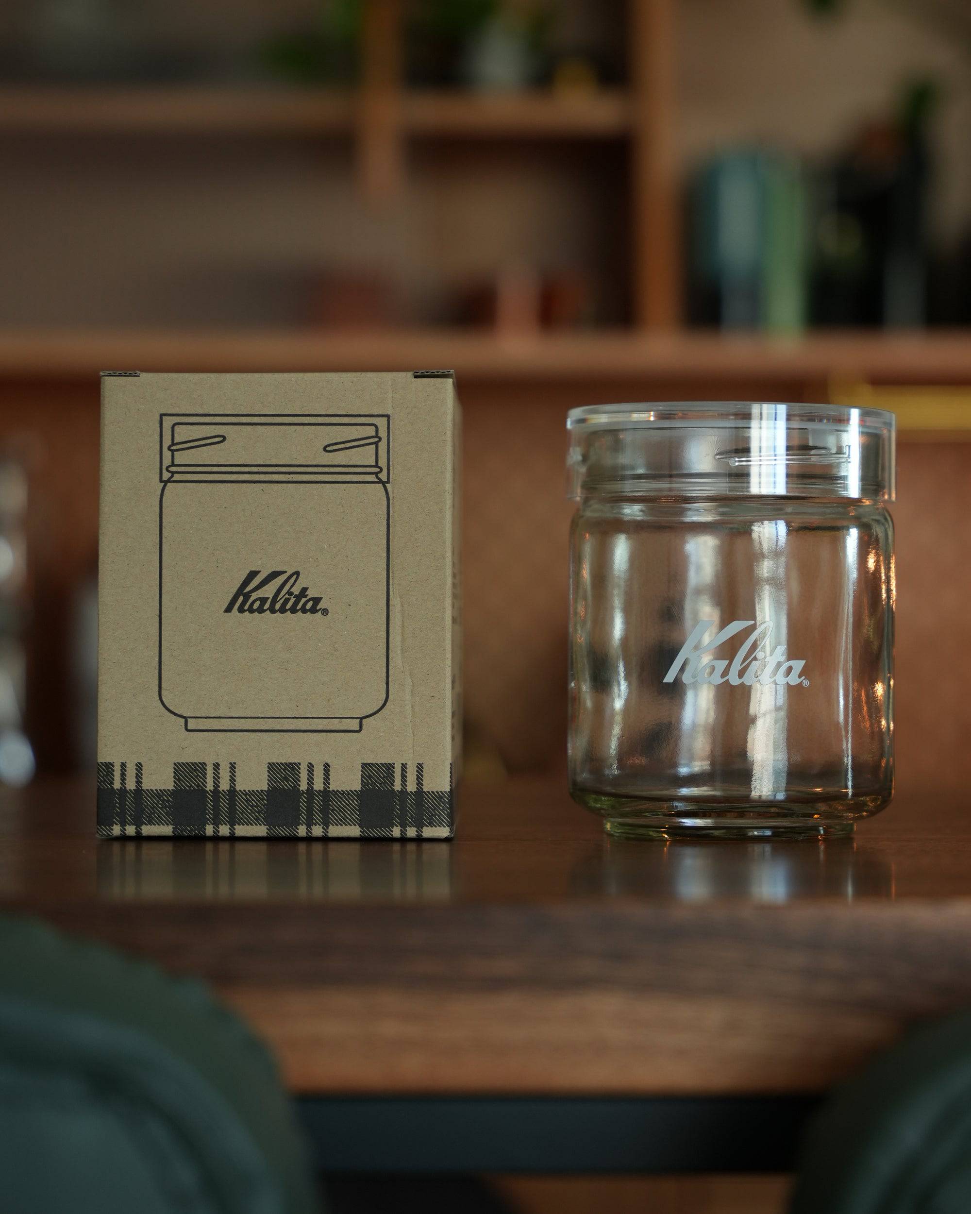 Kalita glass coffee storage jar 250g with packaging box, displayed on wooden surface, showcasing transparent container with brand logo and airtight seal for preserving coffee freshness