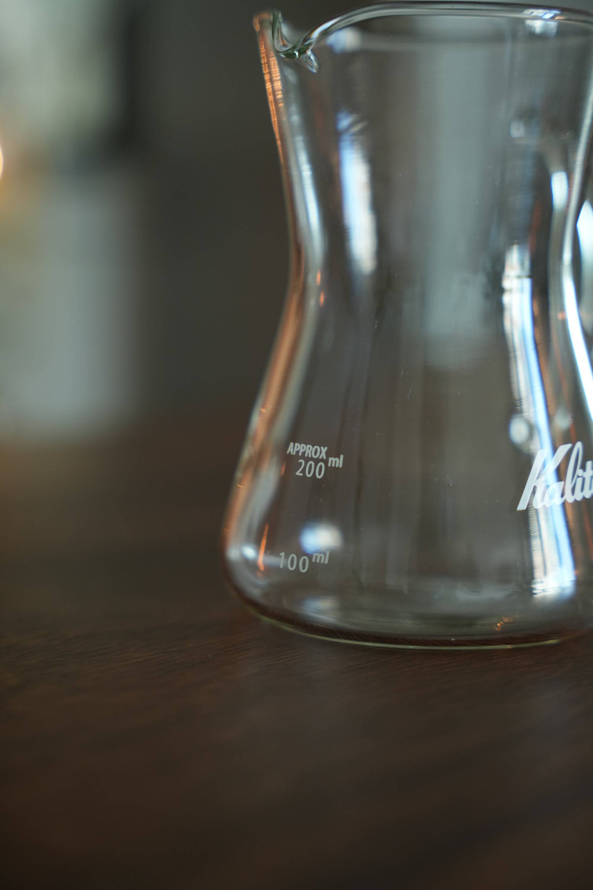 Kalita conical server glass carafe with 100ml and 200ml measurement marks, showcasing its heat-resistant design and Kalita logo, ideal for coffee brewing and serving