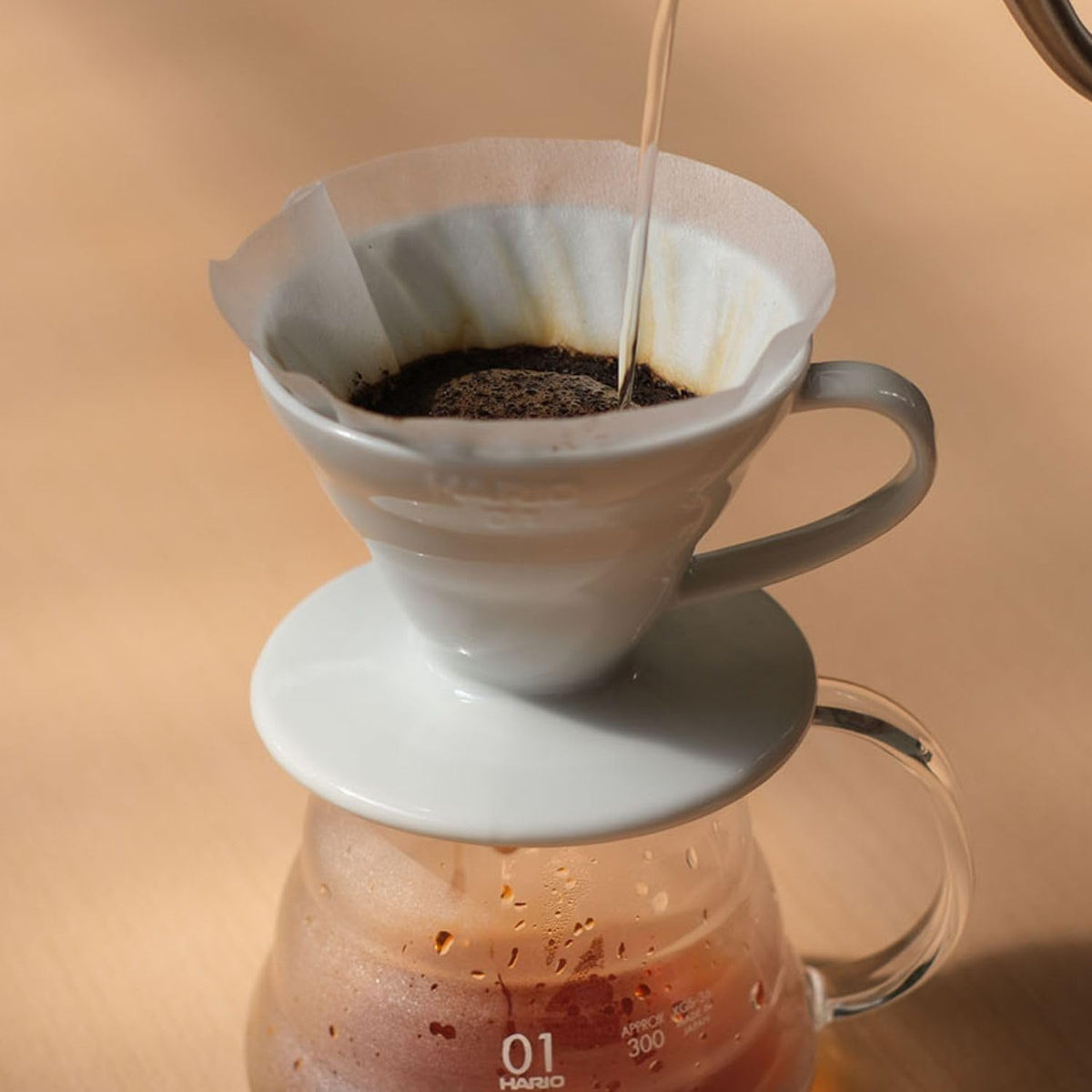 The white ceramic 01 dripper sits on a glass server while brewing.