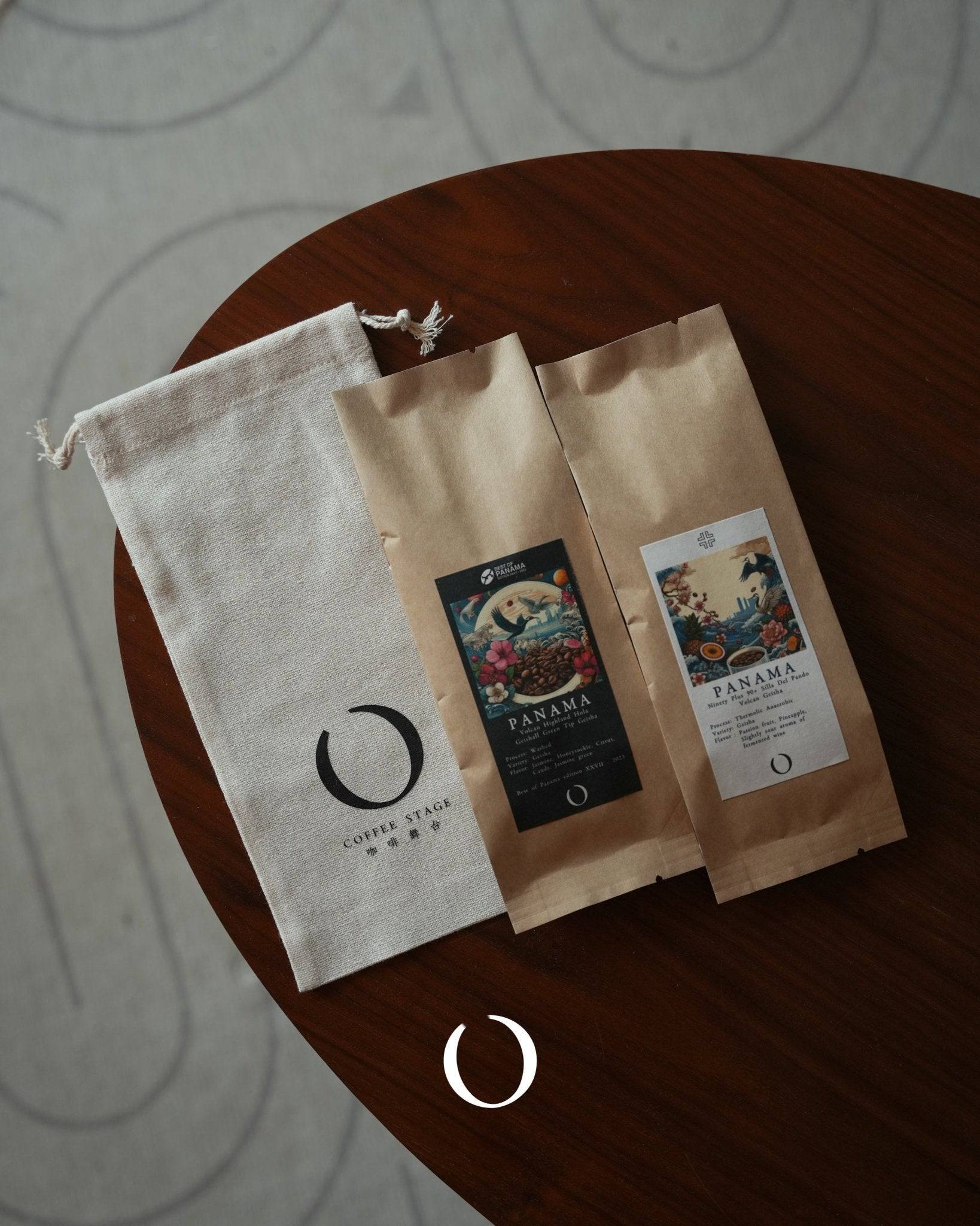 Two coffee bean bags from Ana Sora farm with colorful labels and a canvas pouch on a round wooden table, showcasing Ethiopian Guji specialty coffee