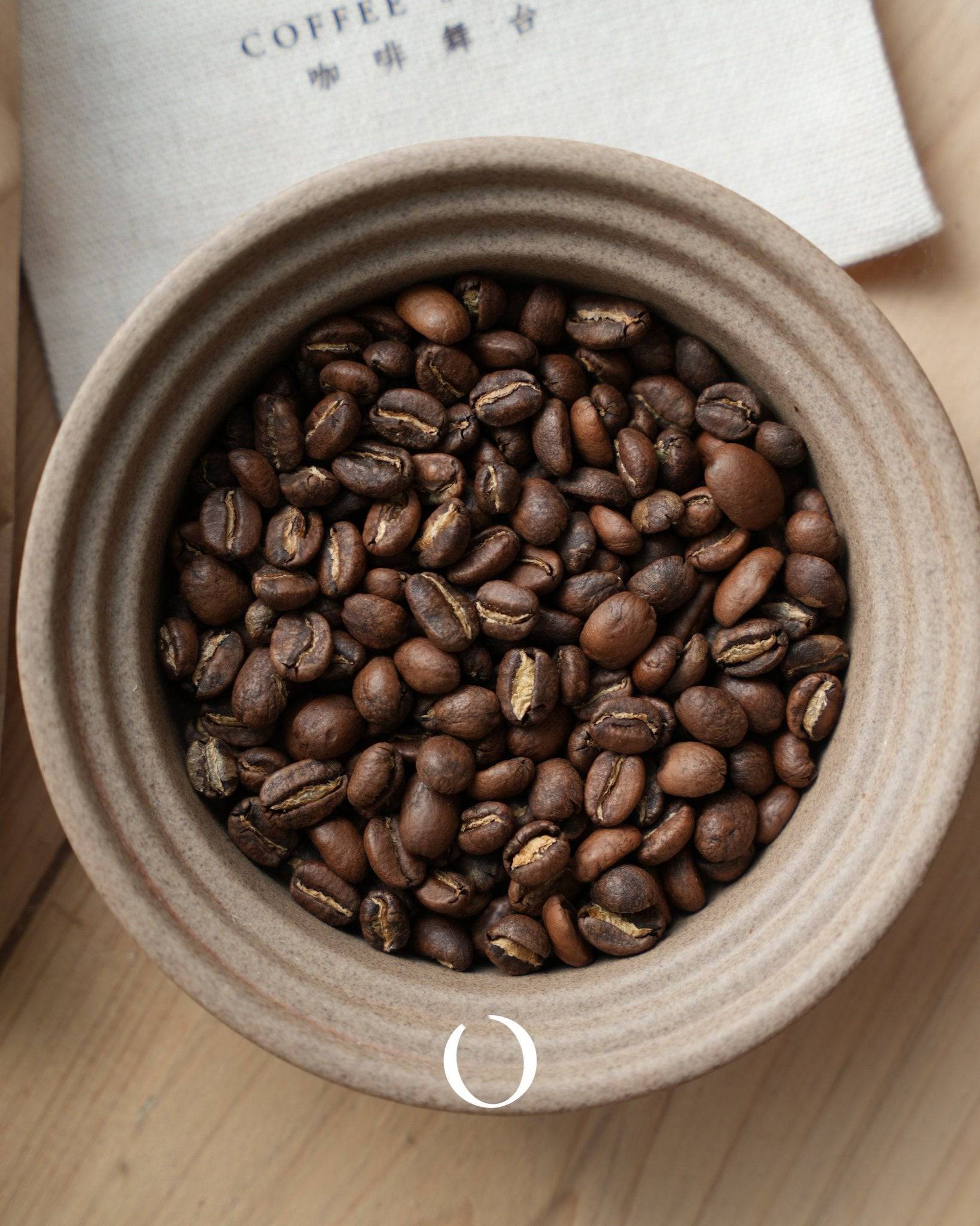 Freshly roasted Ethiopian Ana Sora coffee beans in a ceramic container, showcasing the premium Guji region product with rich, varied colors and textures of the beans.