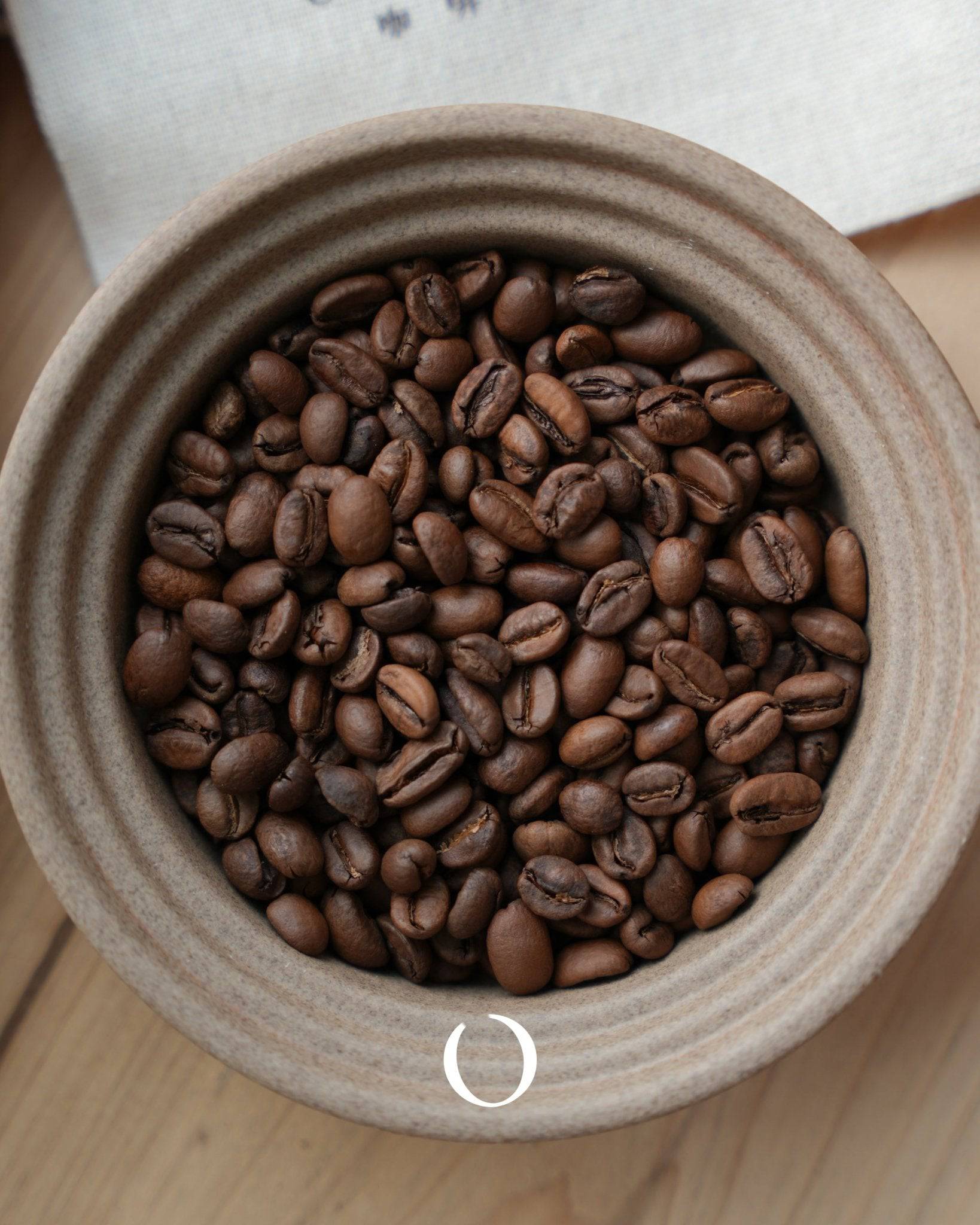 Award-winning Bensa Coffee Ethiopia Sidamo natural processed coffee beans in a ceramic container, showcasing rich brown color and distinctive shape of premium roasted coffee from the Cup of Excellence champion estate.
