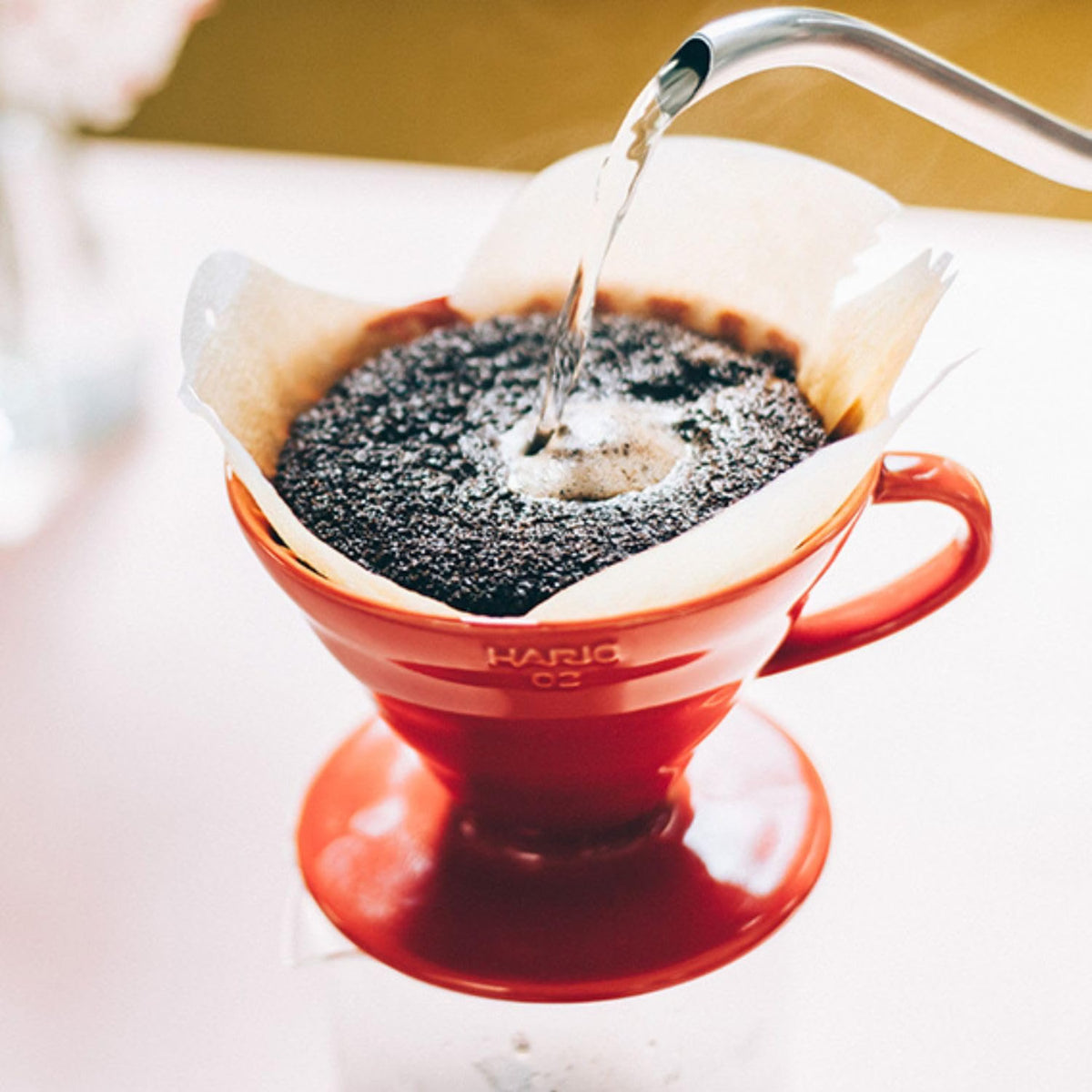 HARIO V60 02 red ceramic dripper, 1–4 cups: V60 02 brewing scene; the gooseneck kettle is a scene prop.