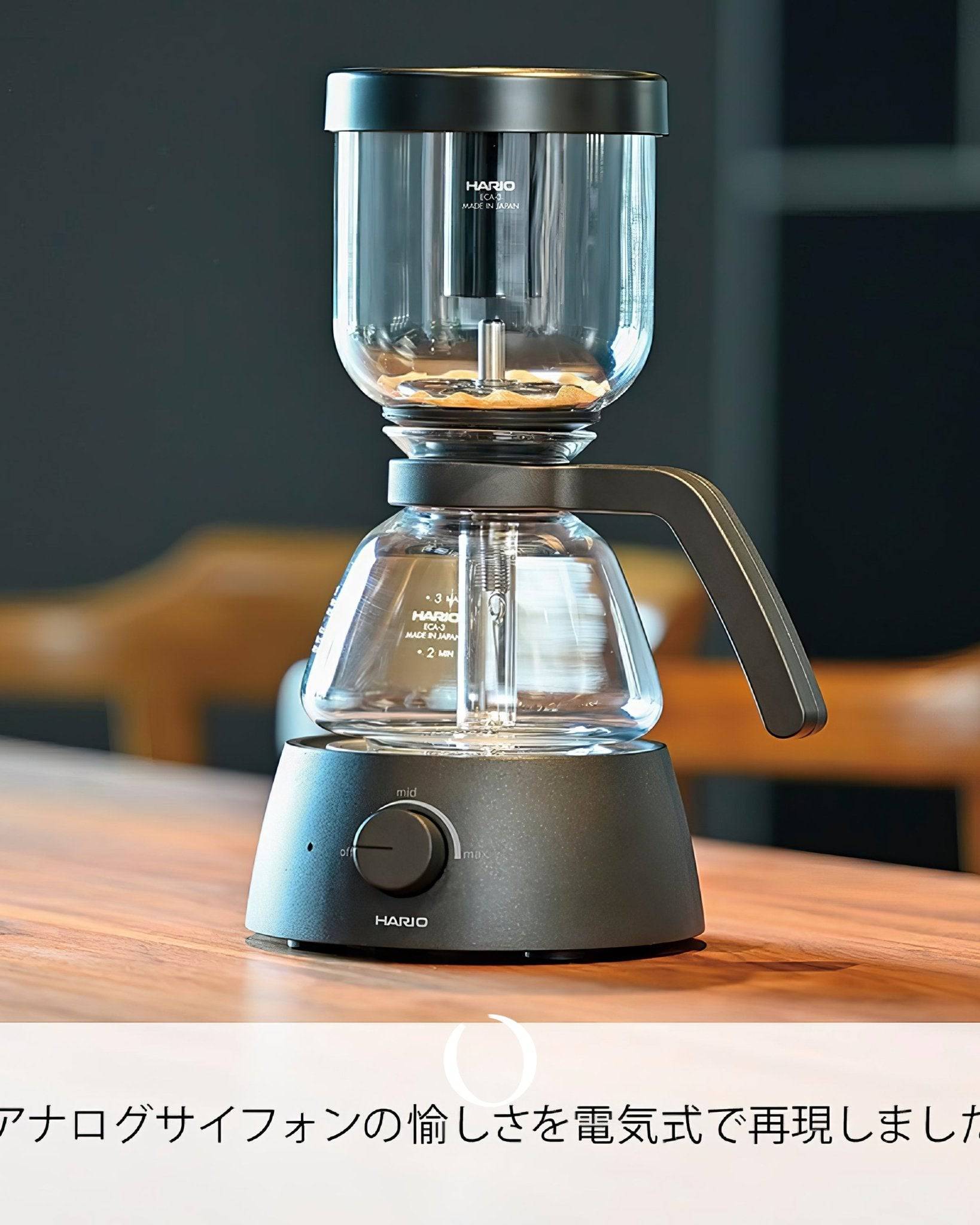 HARIO electric siphon coffee maker ECA-3-B with glass chambers and black base on wooden table, showcasing modern design and brewing process