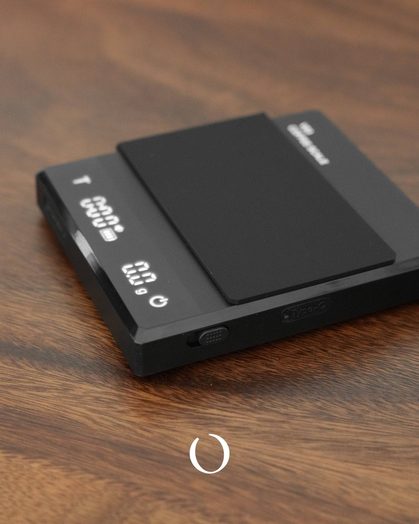Ikape Espresso black digital coffee scale on wooden surface, displaying weight and time, with sleek design and touch-sensitive interface, suitable for precise coffee measurement and brewing