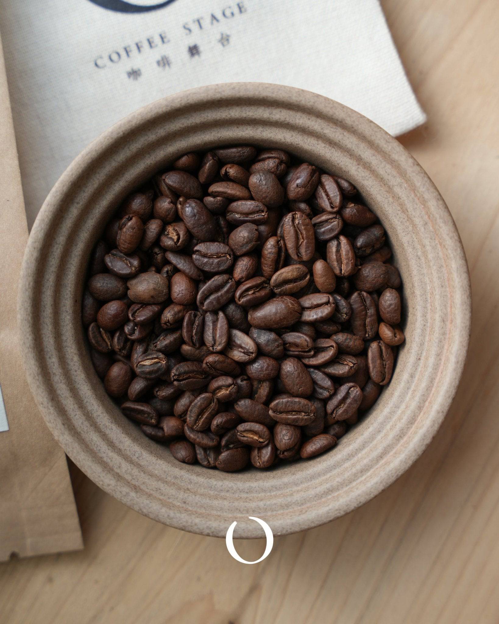 Roasted Ninety Plus Panama Geisha coffee beans in a ceramic bowl, showcasing rich brown color and distinctive bean shape, with Coffee Stage branding visible