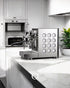 Sleek Rocket Appartamento TCA espresso machine on white kitchen counter, featuring stainless steel body with circular pattern design, portafilter attached, and steam wand visible, showcasing modern aesthetic and professional capabilities.