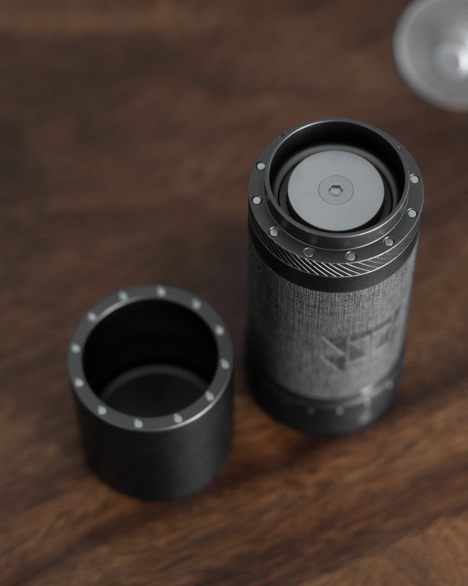 1zpresso J MAXS manual coffee grinder with detachable magnetic grounds container, showcasing precision adjustment rings and sleek black metal design on wooden surface