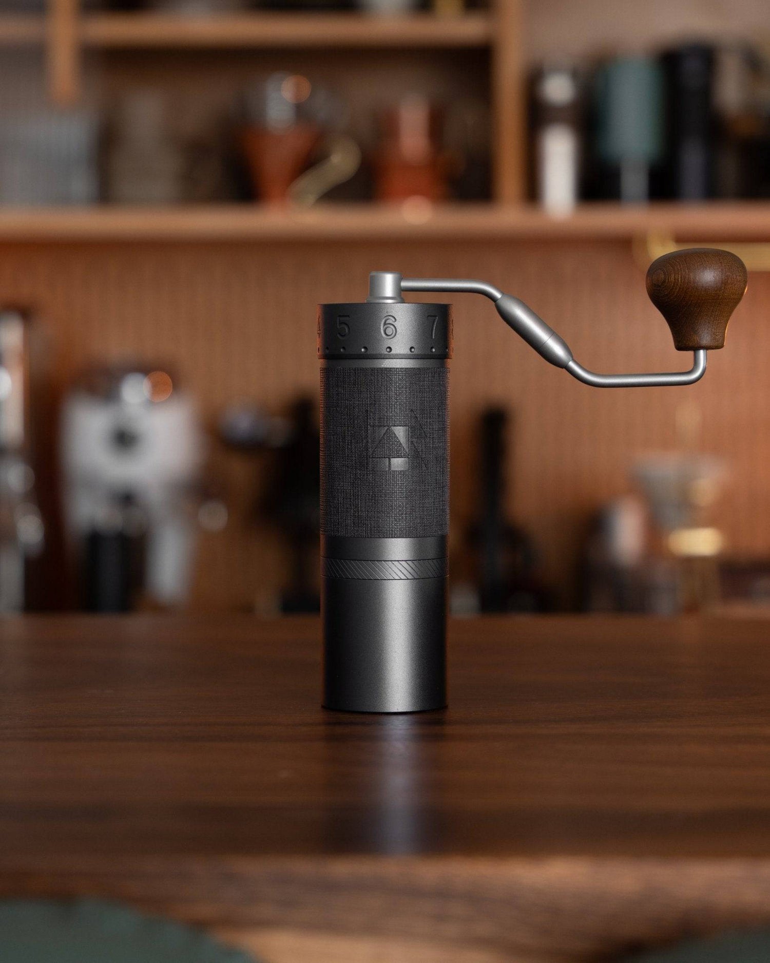 1zpresso J MAXS manual coffee grinder with wooden handle on wooden table, showcasing its sleek black design and precise adjustment ring, ideal for espresso grinding