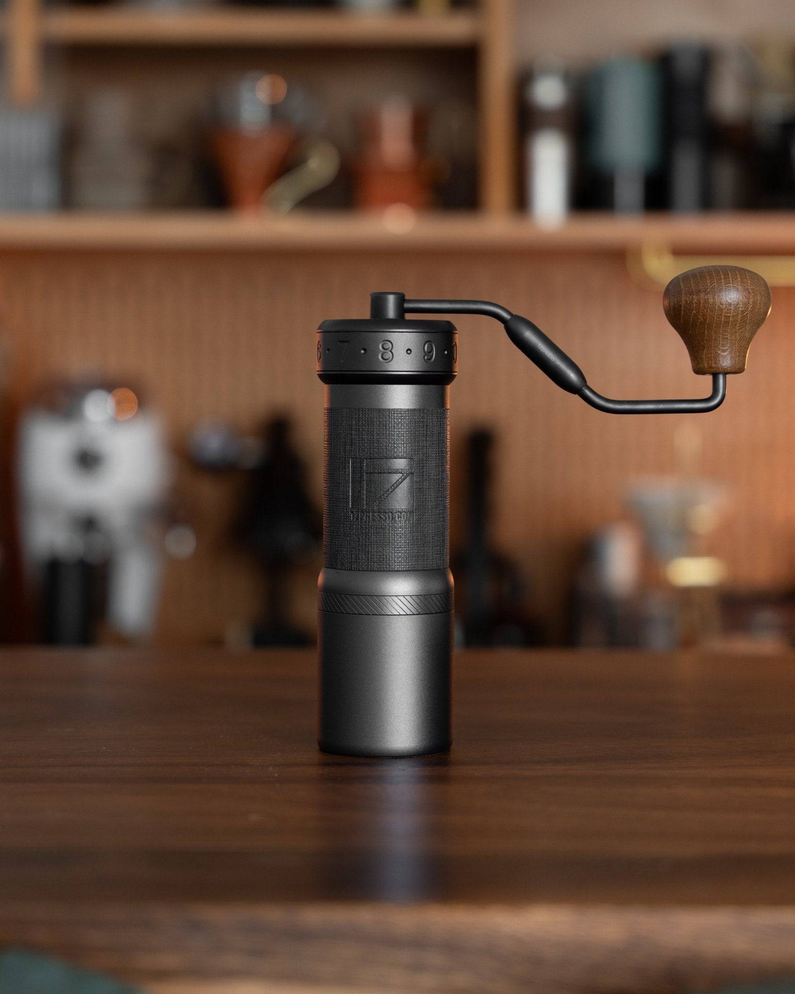 1Zpresso K-Ultra manual coffee grinder with foldable handle on wooden surface, showcasing sleek black design and compact size, perfect for precision grinding at home or while traveling