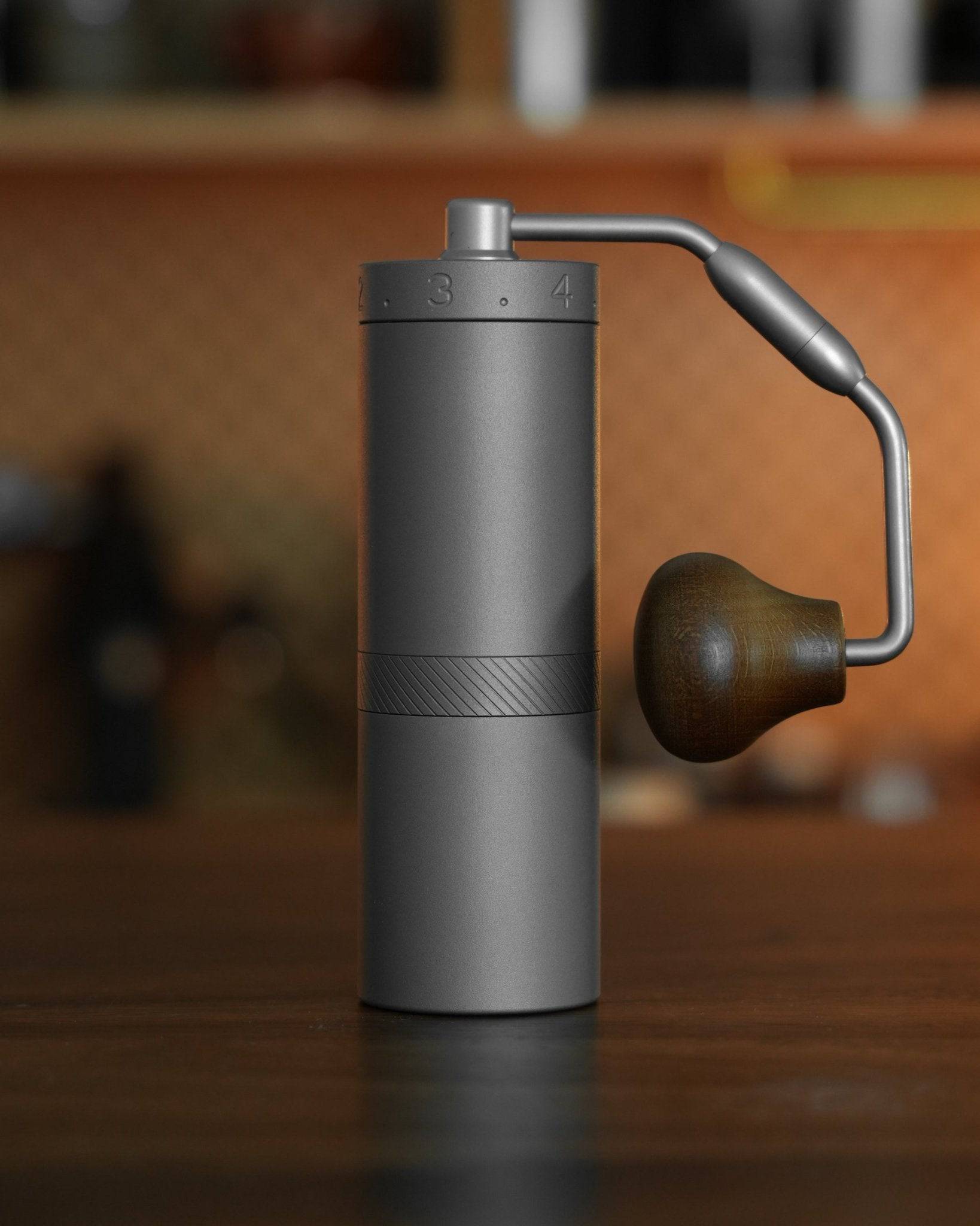 1Zpresso X-Ultra manual coffee grinder with sleek metal body, adjustable grind settings, and ergonomic wooden handle, positioned on wooden surface in kitchen setting