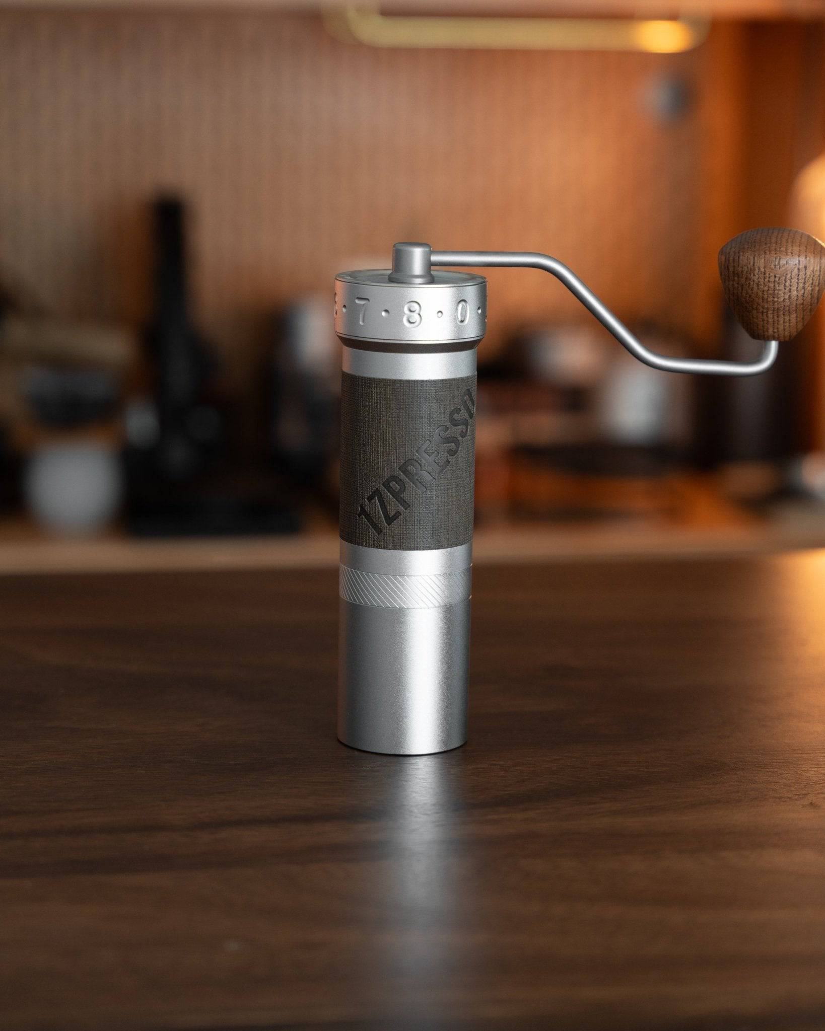 1zpresso ZP6 manual coffee grinder on wooden table, featuring sleek silver and gray design with adjustable grind settings and ergonomic handle, showcasing professional-grade grinding capability for pour-over coffee enthusiasts