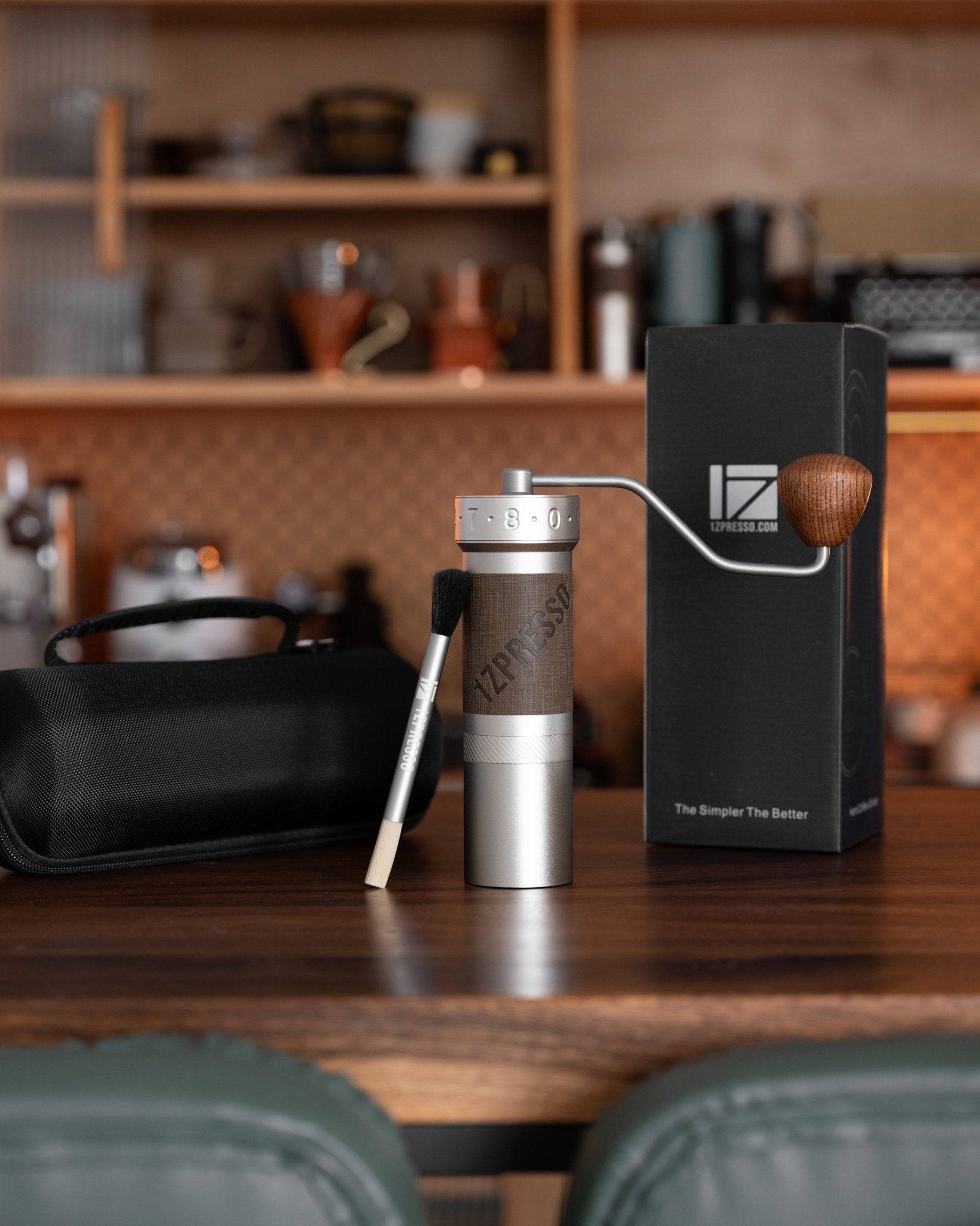 1zpresso ZP6 manual coffee grinder displayed on wooden counter with packaging, cleaning brush, and coffee accessories in background, showcasing premium design and functionality for coffee enthusiasts