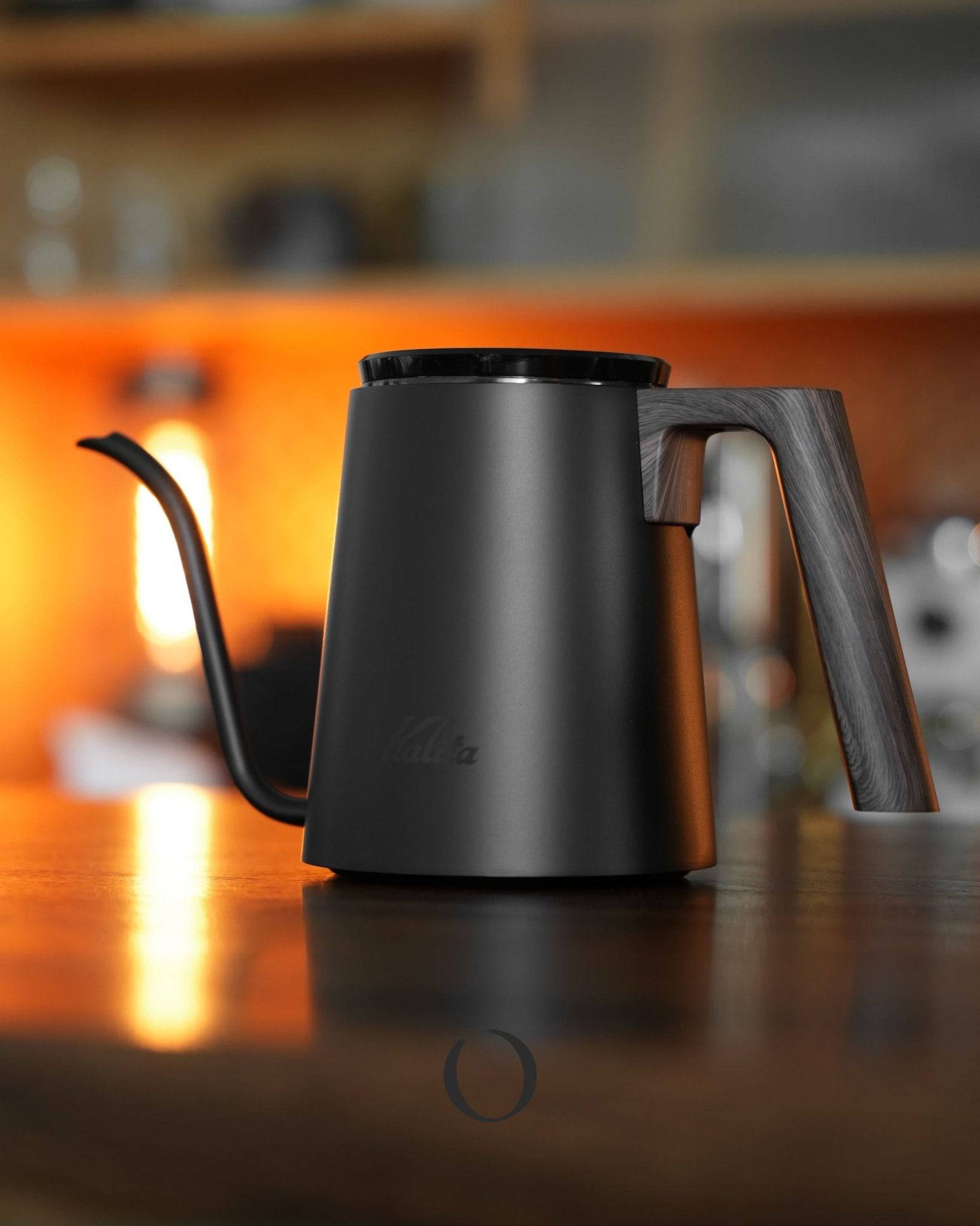 Kalita KDP-800 pour-over kettle with black walnut wood pattern, 800ml capacity, elegant design, award-winning gooseneck spout for precise pouring, stainless steel body, displayed on warm-lit kitchen counter