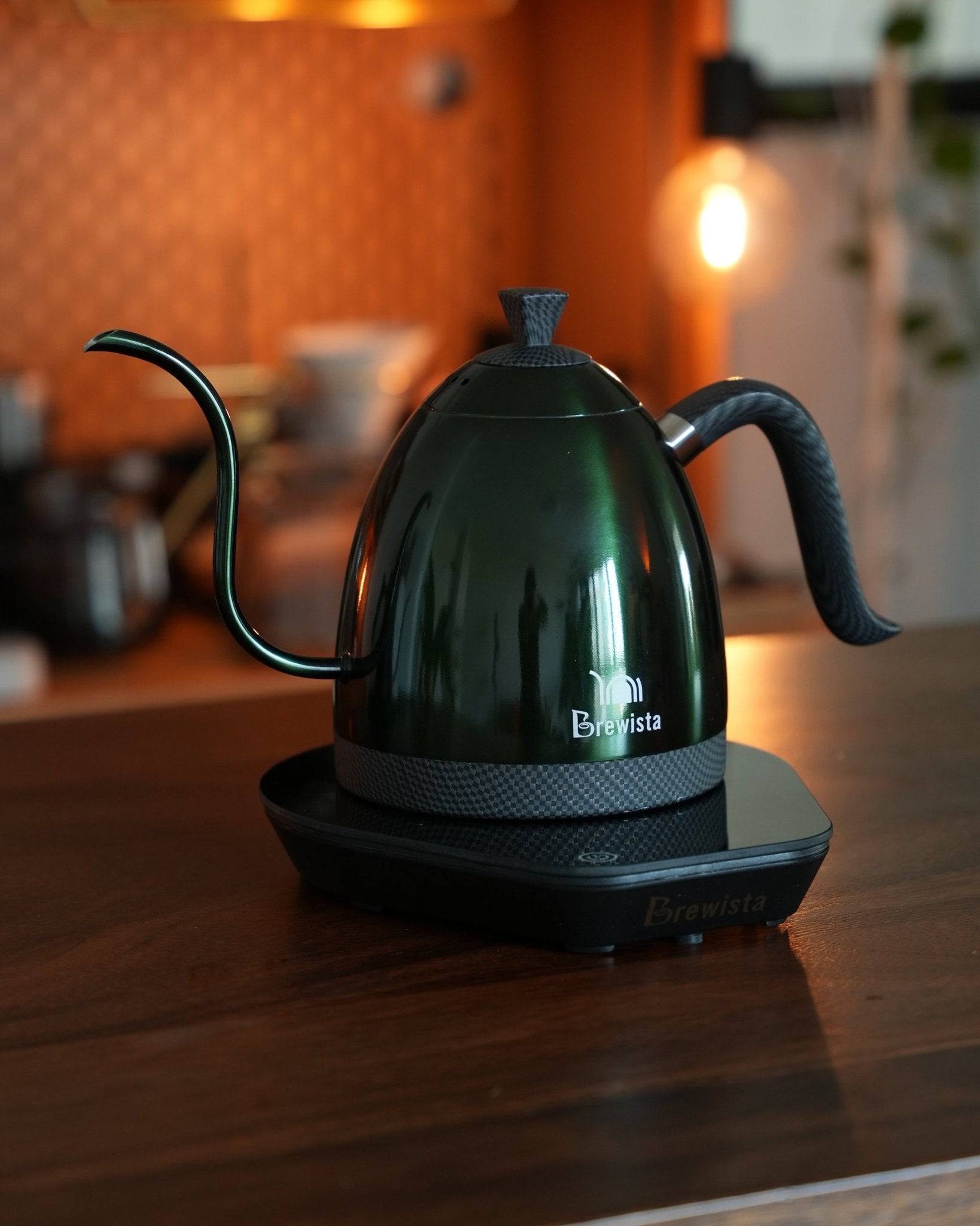 Brewista Artisan temperature-controlled kettle with gooseneck spout on electric base, showcasing sleek black design in warm, ambient kitchen setting