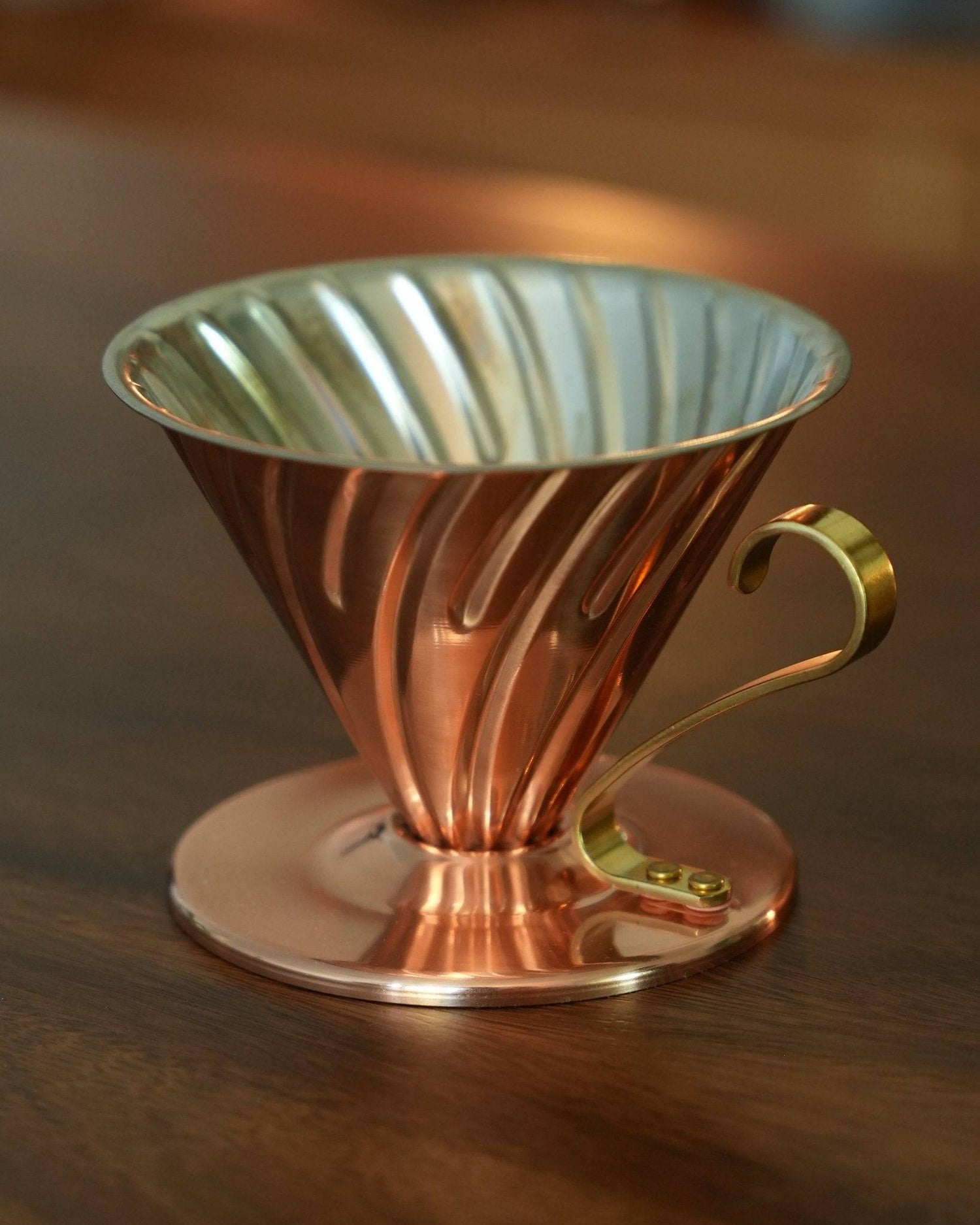 HARIO V60 02 copper pour-over coffee dripper with conical shape, spiral ribs, and brass handle, showcasing Japanese craftsmanship and superior heat conductivity for optimal coffee extraction