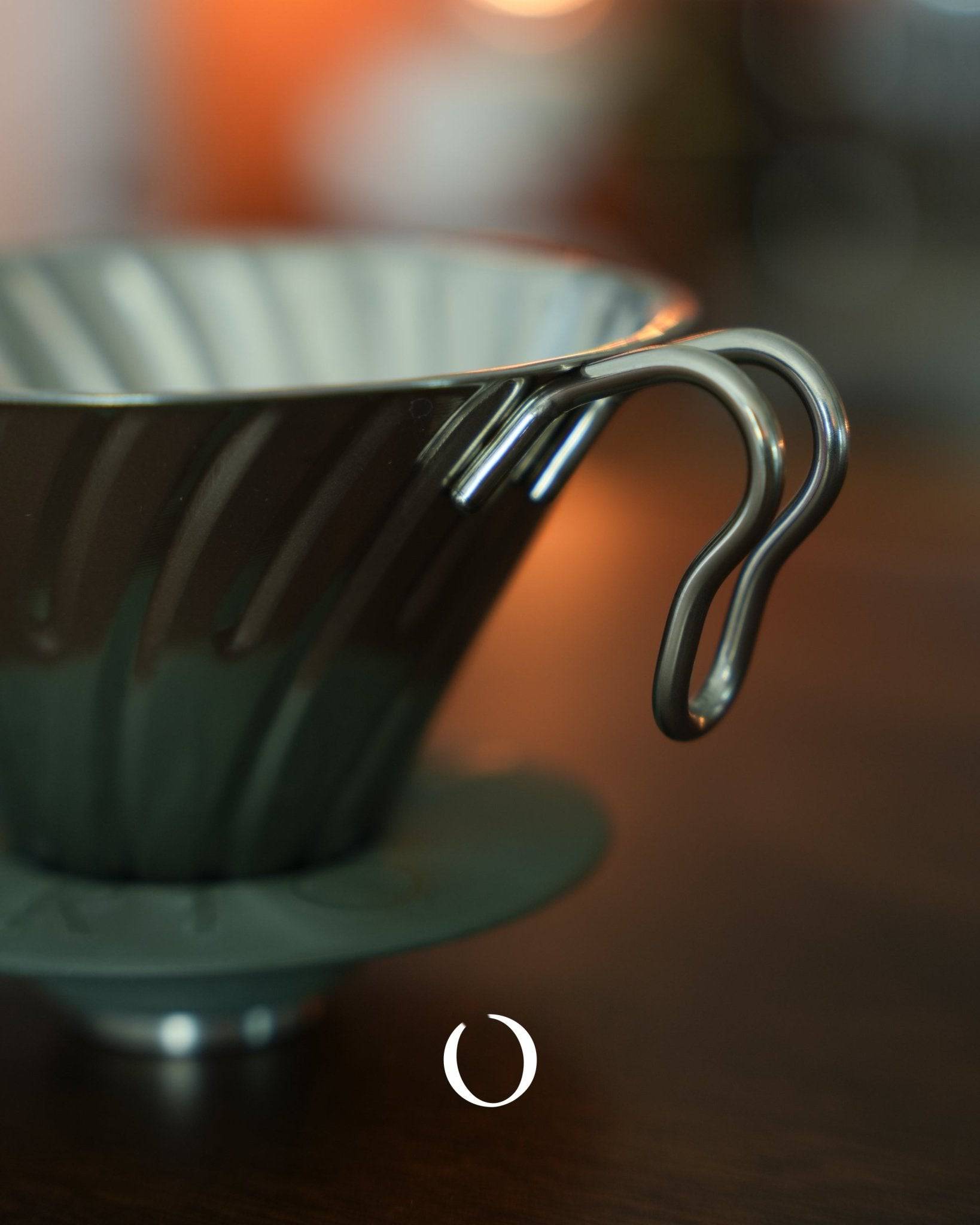 HARIO V60 02 stainless steel coffee dripper in silver, showcasing its conical design and spiral ribs for optimal brewing, with a close-up view of its durable and easy-to-clean metal construction