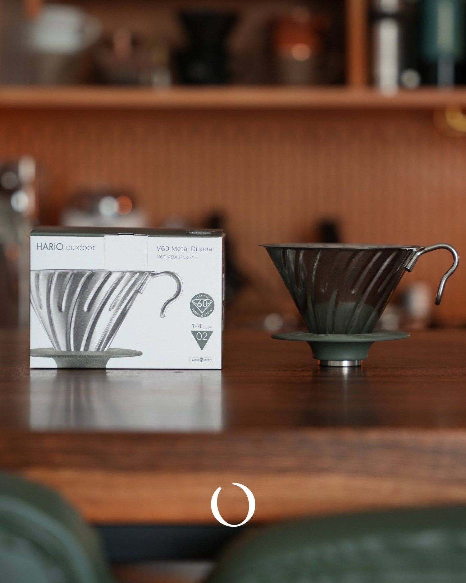 HARIO V60 02 stainless steel metal dripper in silver color displayed on wooden surface with product box, showcasing conical design and spiral ribs for optimal coffee extraction
