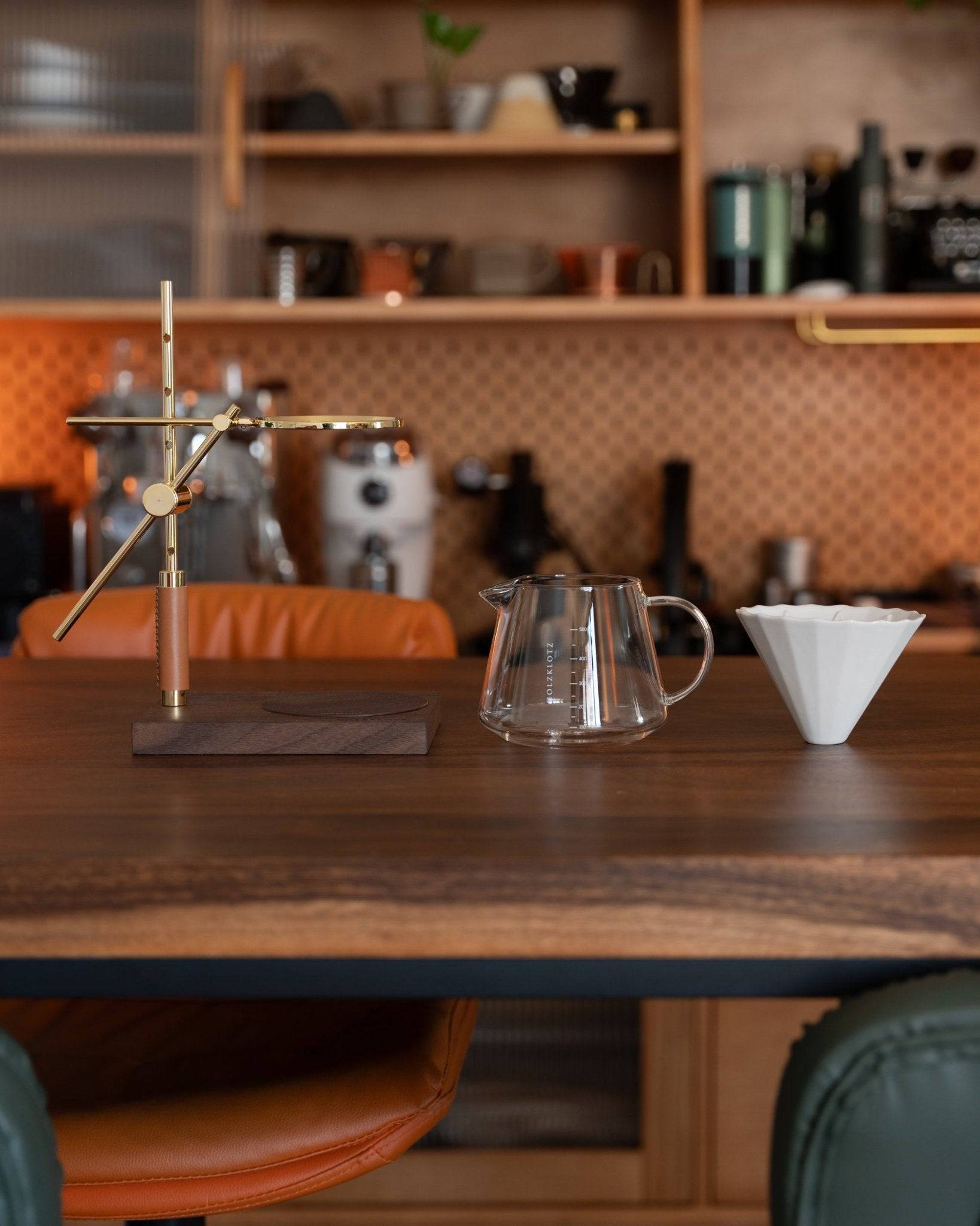 Elegant pour-over coffee set featuring gold-plated stand, ceramic dripper, and glass carafe on wooden table in stylish kitchen, showcasing Holzklotz&