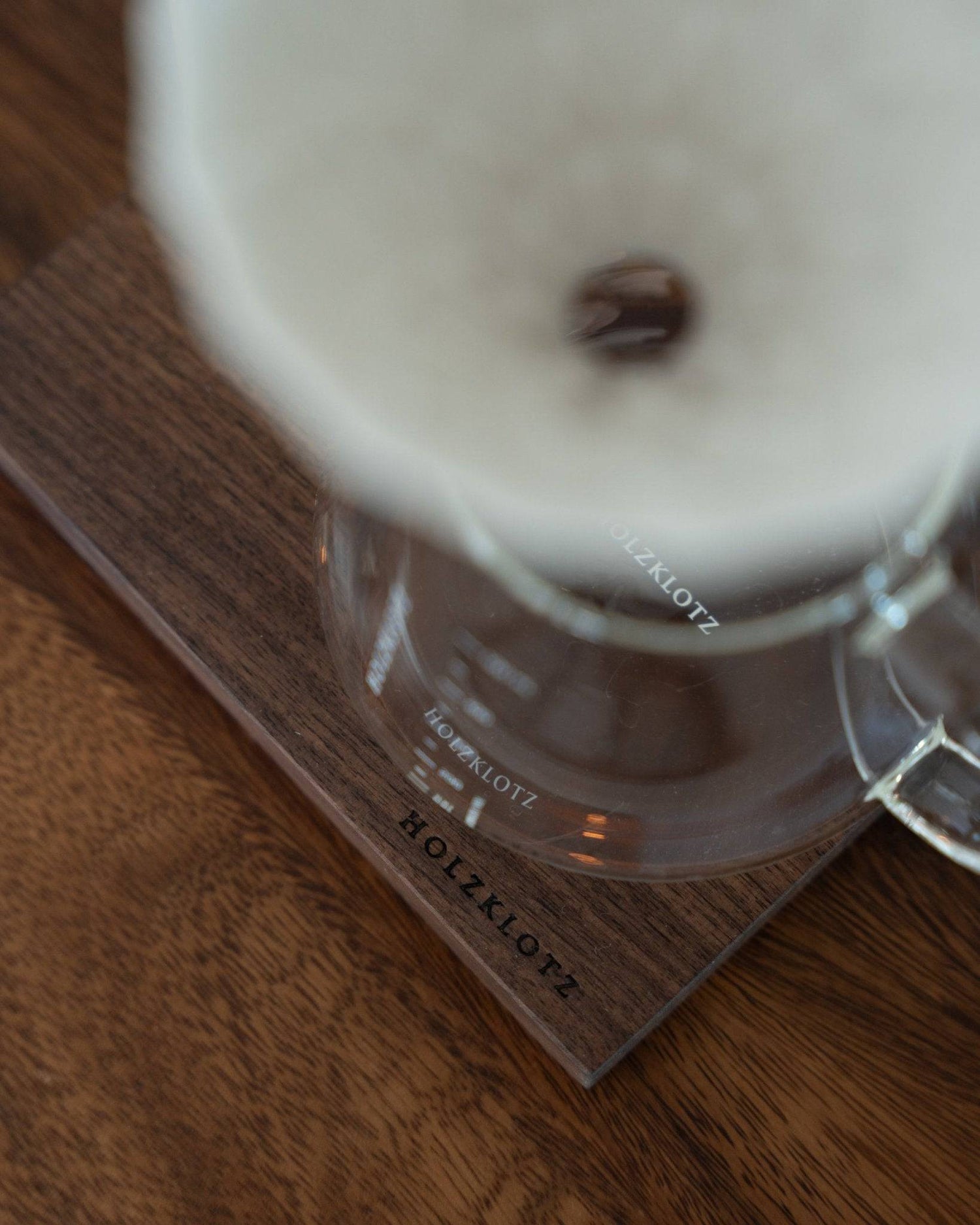 Close-up of Holzklotz coffee dripper set featuring white ceramic filter, glass carafe, and wooden base, showcasing elegant design and premium materials for pour-over coffee brewing