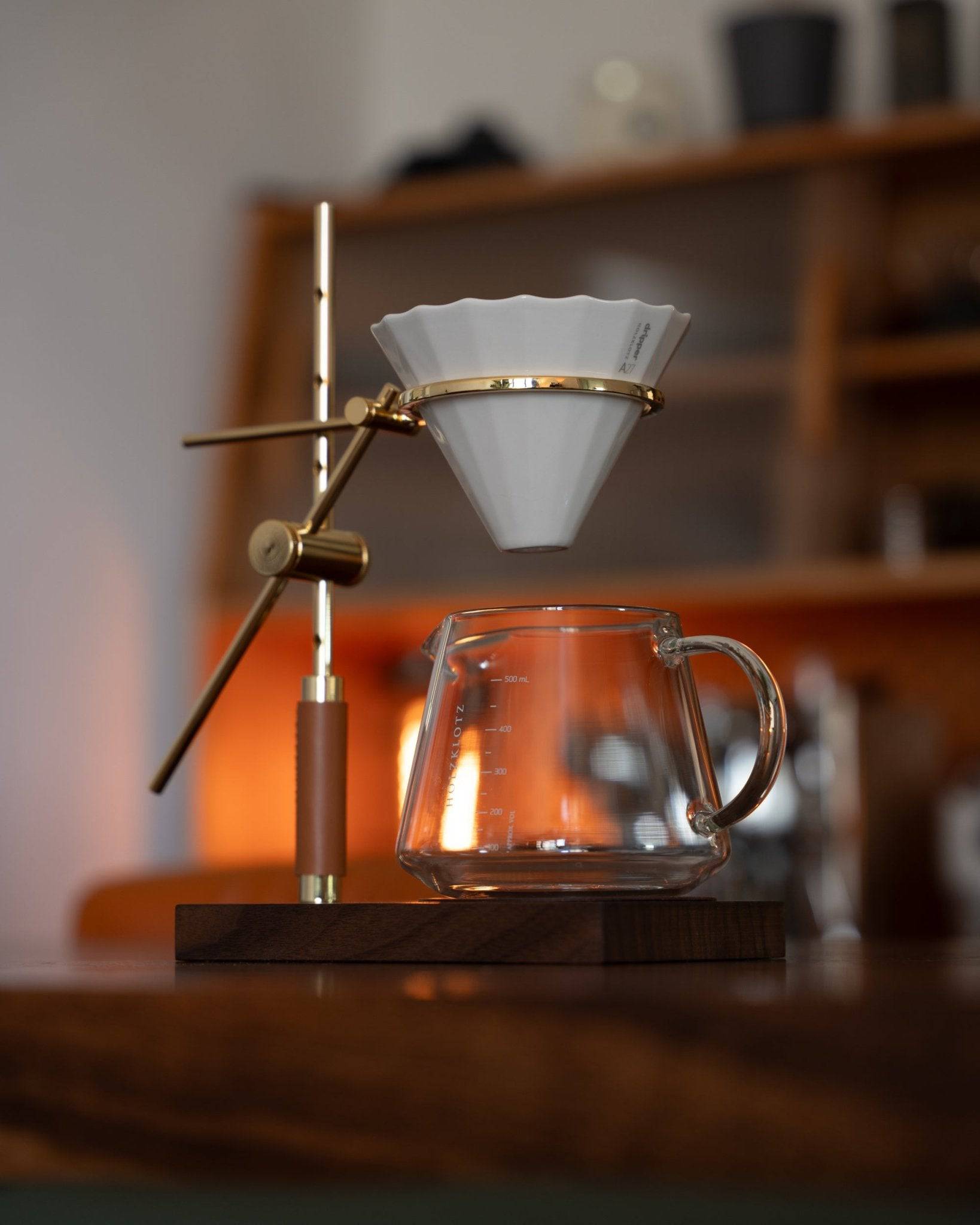 Elegant Holzklotz pour-over coffee set featuring gold-plated brass stand, ceramic filter, and glass carafe on wooden base, showcasing craftsmanship and attention to detail for premium home brewing experience
