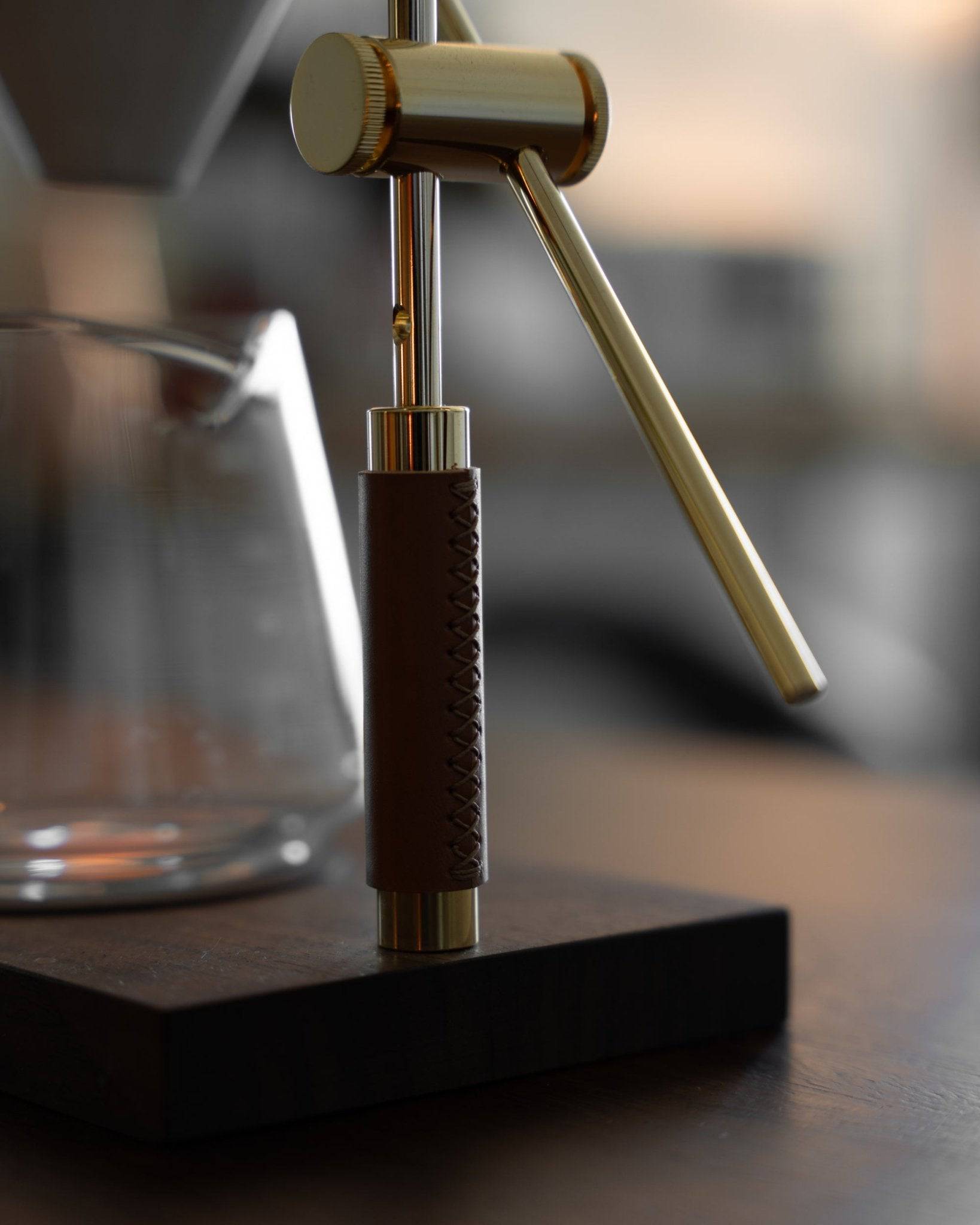 Elegant gold-plated pour-over coffee stand with leather-wrapped handle, showcasing Holzklotz&