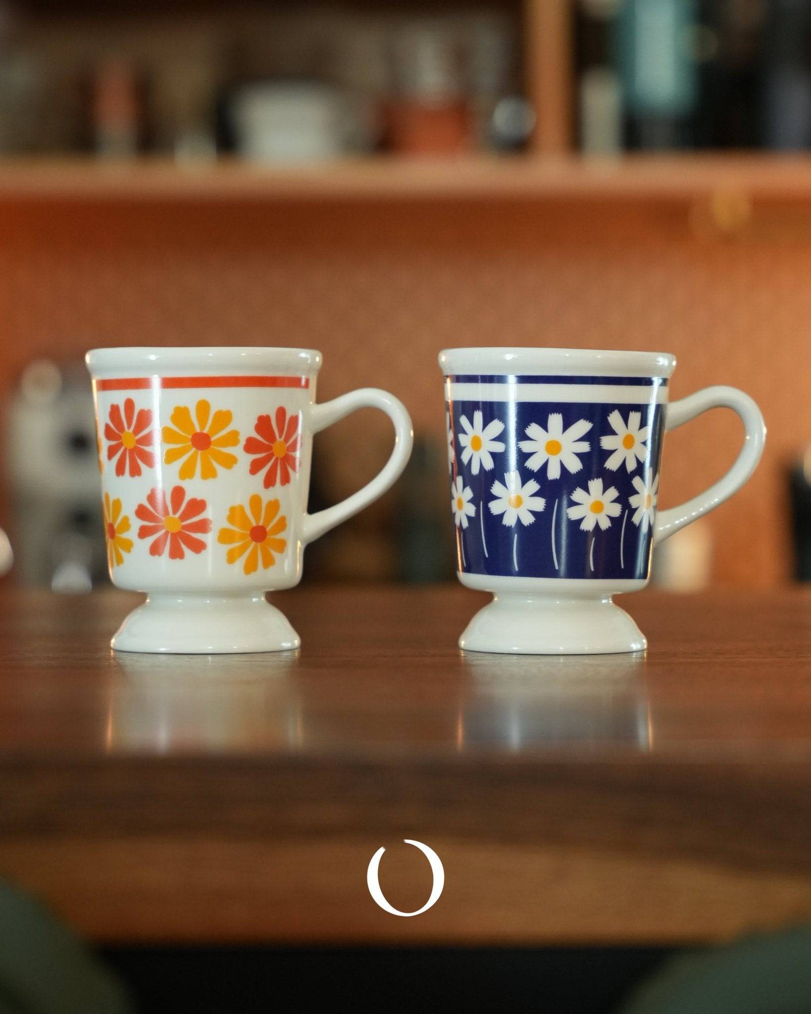 Vintage Showa-era coffee cups with floral designs, one orange and one deep blue, showcasing ippinsha&