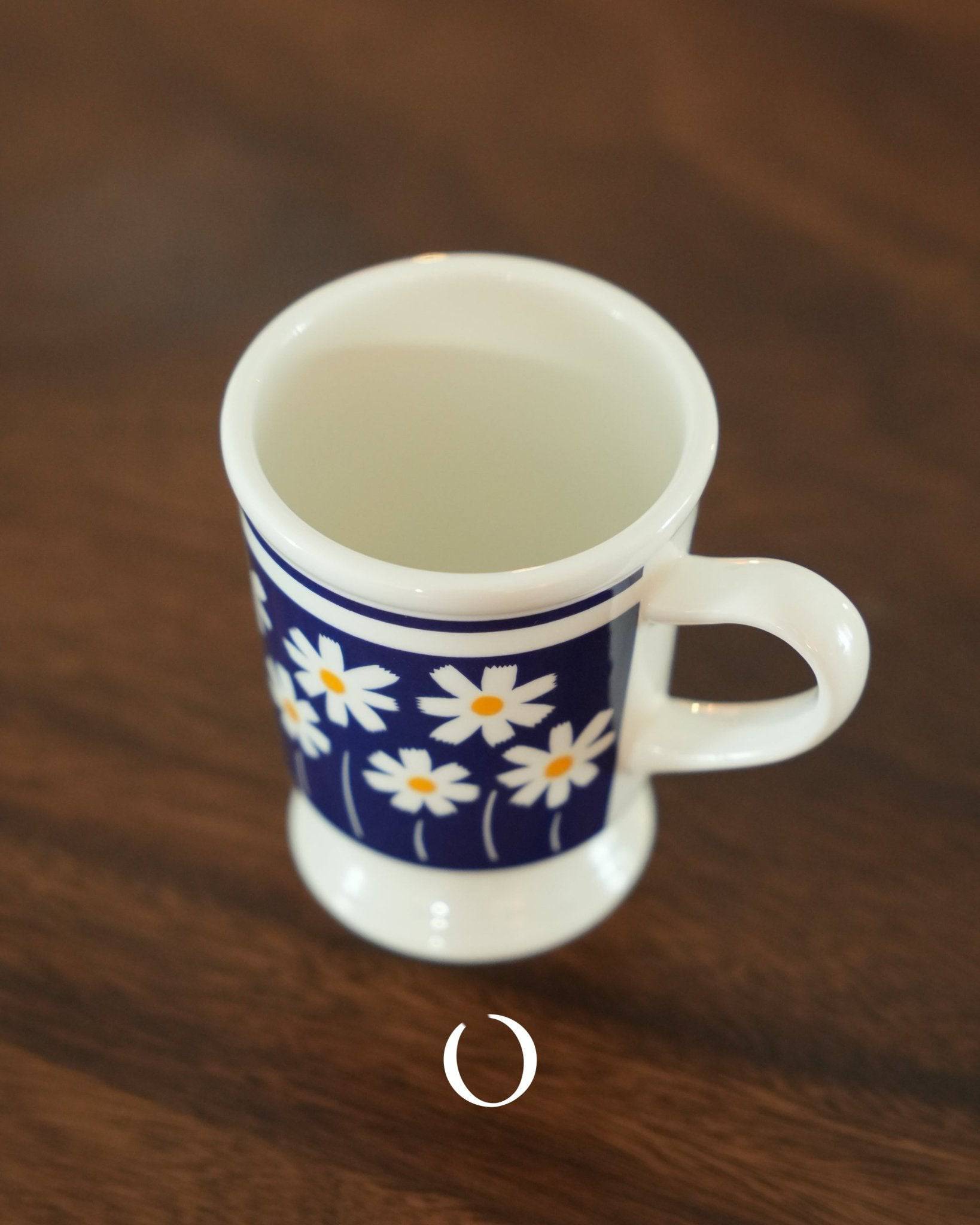 Vintage Showa-era coffee cup with white daisies on deep blue background, ippinsha brand, 250ml capacity, ceramic mug on wooden surface, retro floral design, nostalgic Japanese style