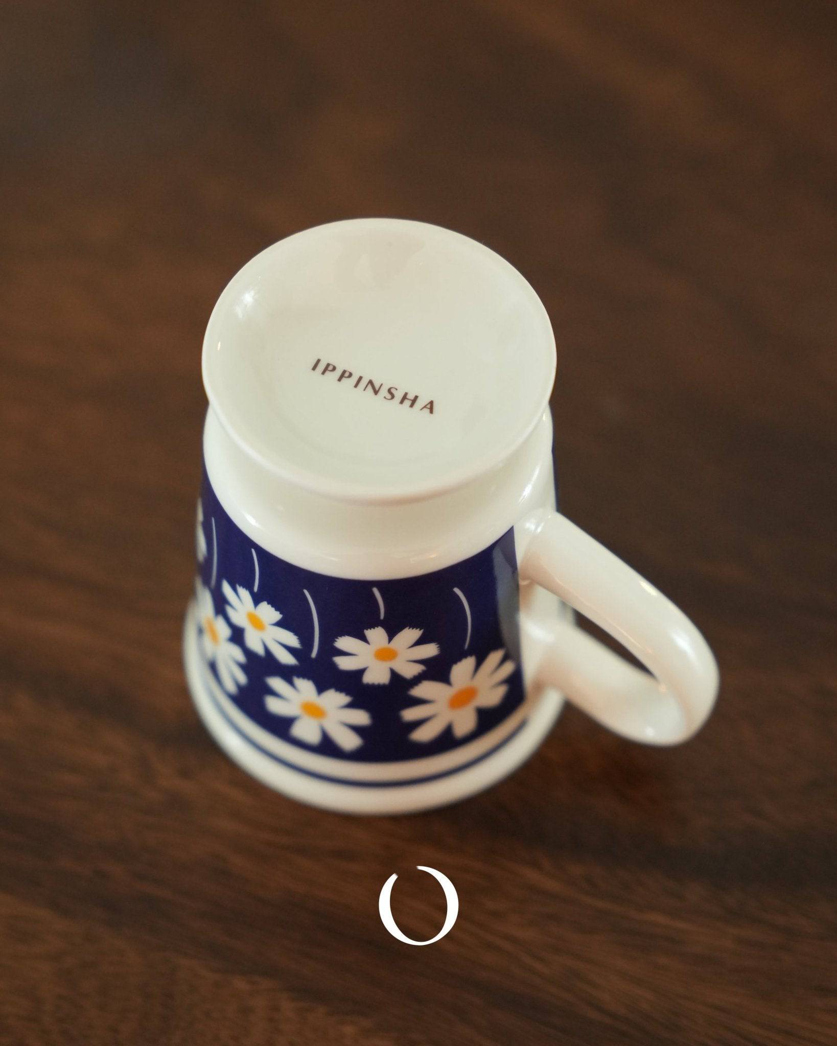 Ippinsha vintage coffee cup with white lid and handle, deep blue body decorated with delicate daisy floral pattern, showcasing Showa era nostalgic design on wooden surface