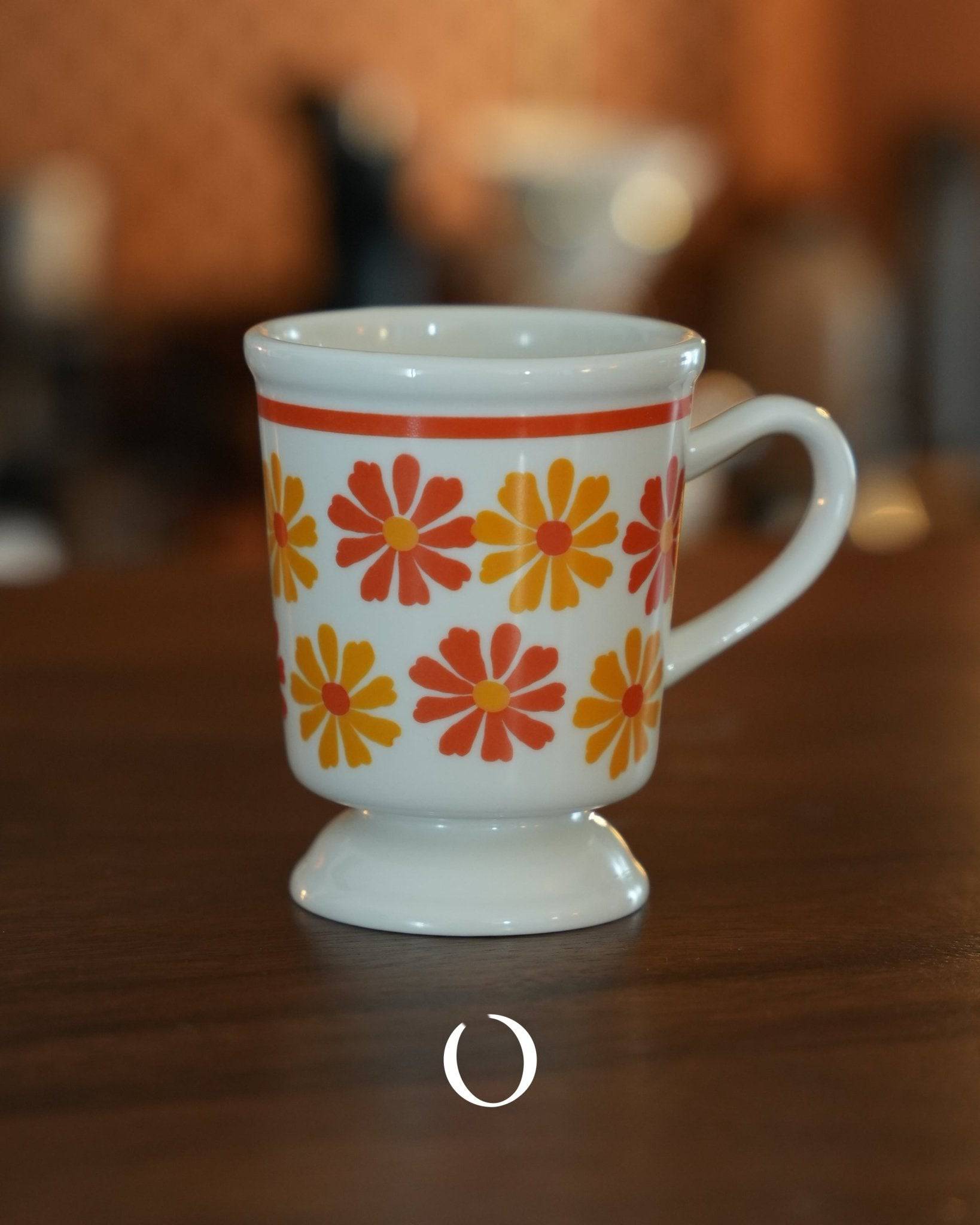 Vintage ippinsha ceramic coffee cup with orange and yellow daisy pattern, 250ml capacity, Showa era inspired design, on wooden surface