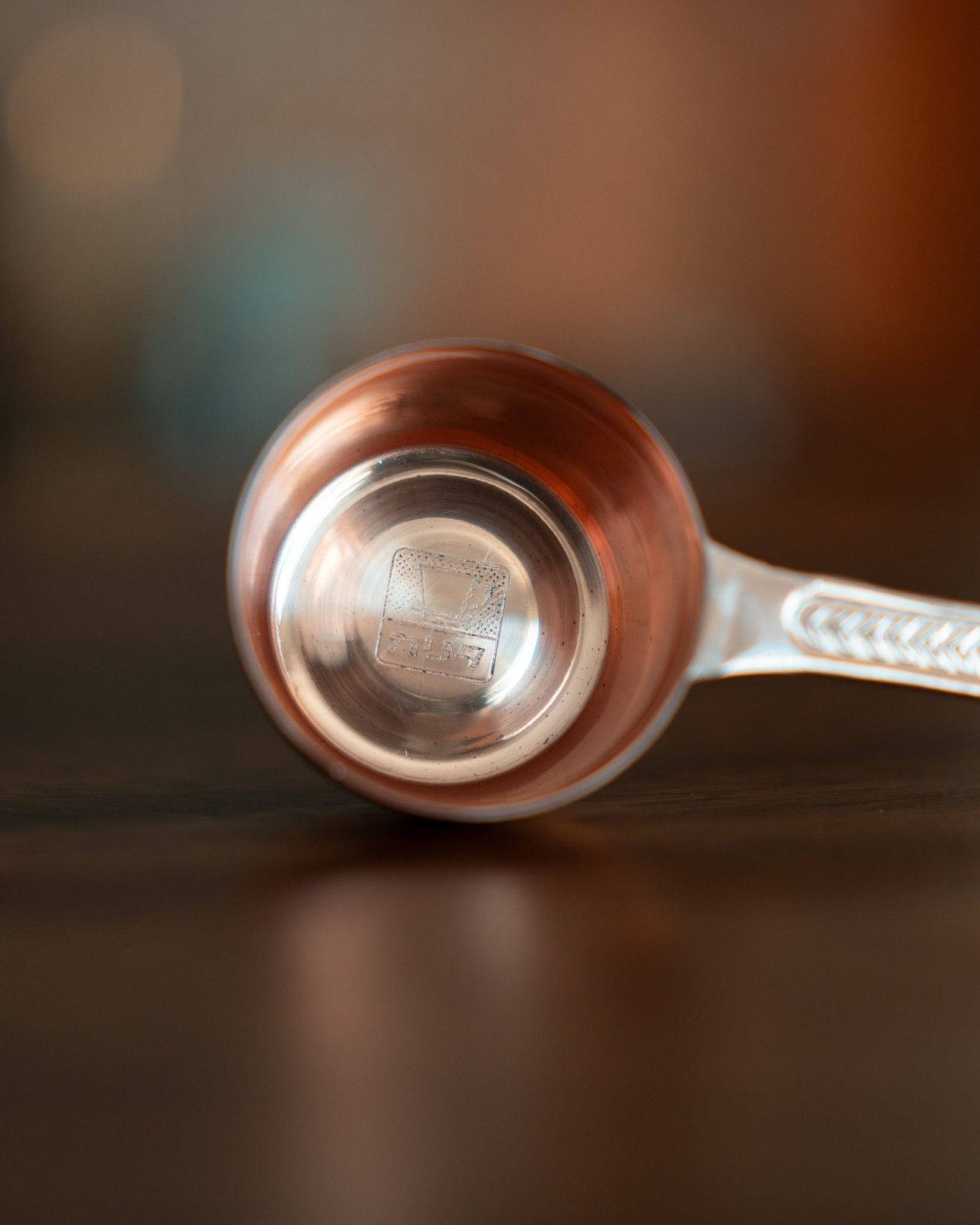 Kalita copper coffee scoop with laurel wreath pattern, 10g capacity, rose gold color, elegant design, precise measurement tool for coffee beans, close-up view on wooden surface
