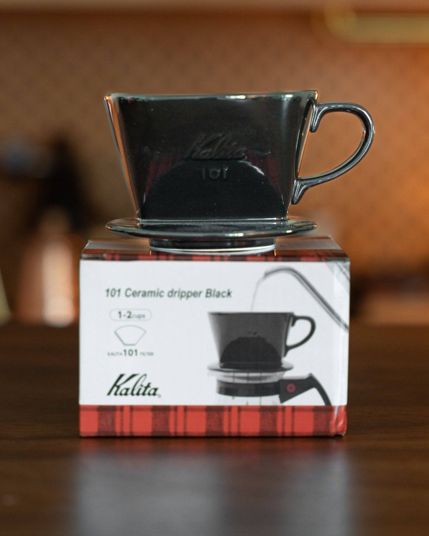 Kalita 101 black ceramic coffee dripper displayed on its product box, showcasing the classic conical design and glossy finish for premium pour-over brewing