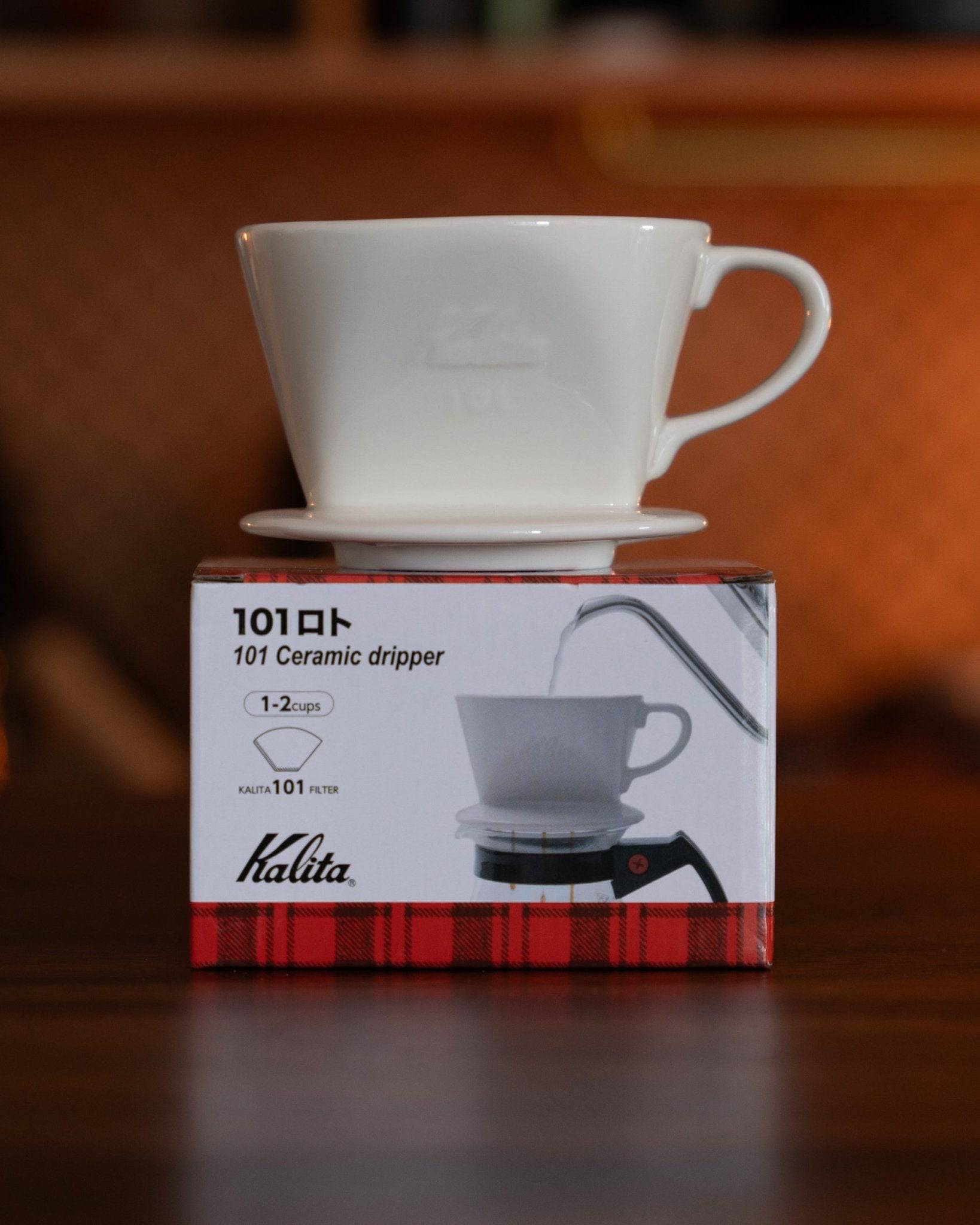 Kalita 101 white ceramic coffee dripper on its product box, showcasing the elegant cone-shaped design and high-quality porcelain material, ideal for brewing 1-2 cups of pour-over coffee