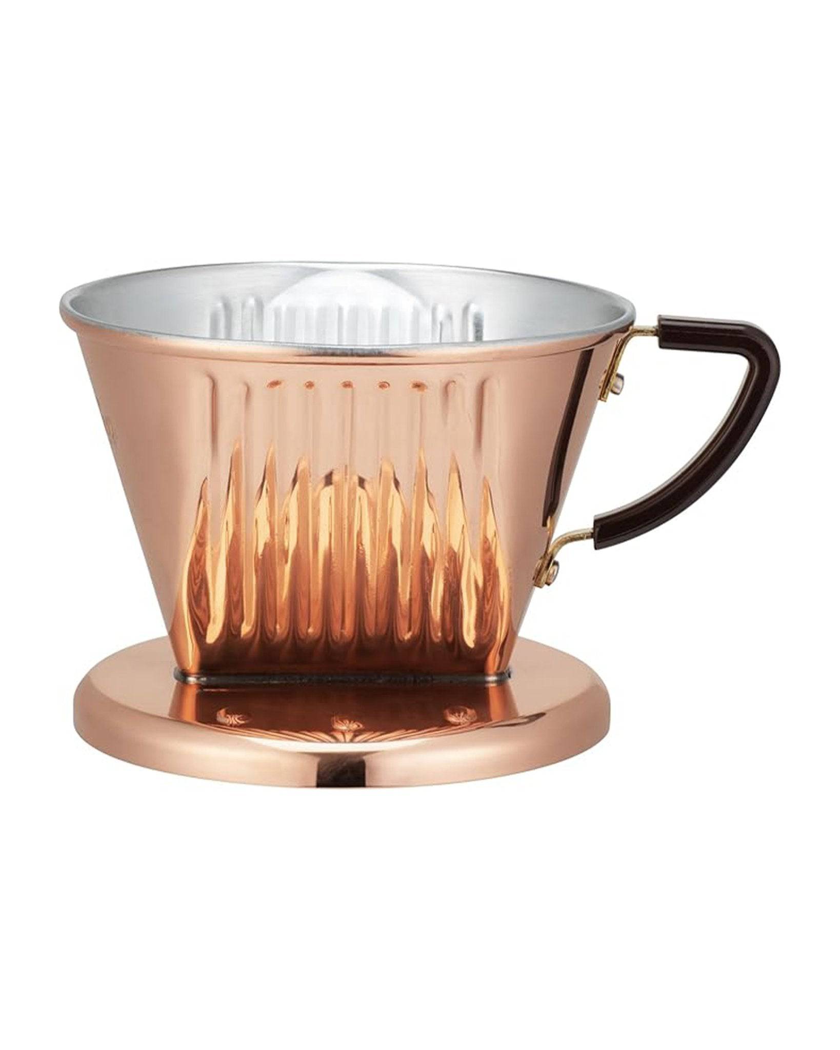 Copper KALITA coffee dripper with three-hole design, featuring a conical shape, ribbed interior, and dark handle. The dripper sits on a matching copper base, showcasing a premium handcrafted appearance for optimal coffee extraction.
