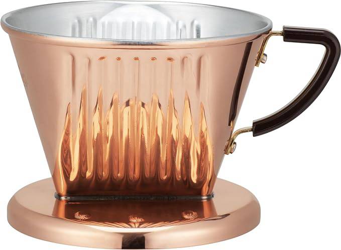 Copper KALITA pour-over coffee dripper with three-hole design, featuring a cone shape, ribbed interior, and dark handle, sitting on a matching copper base