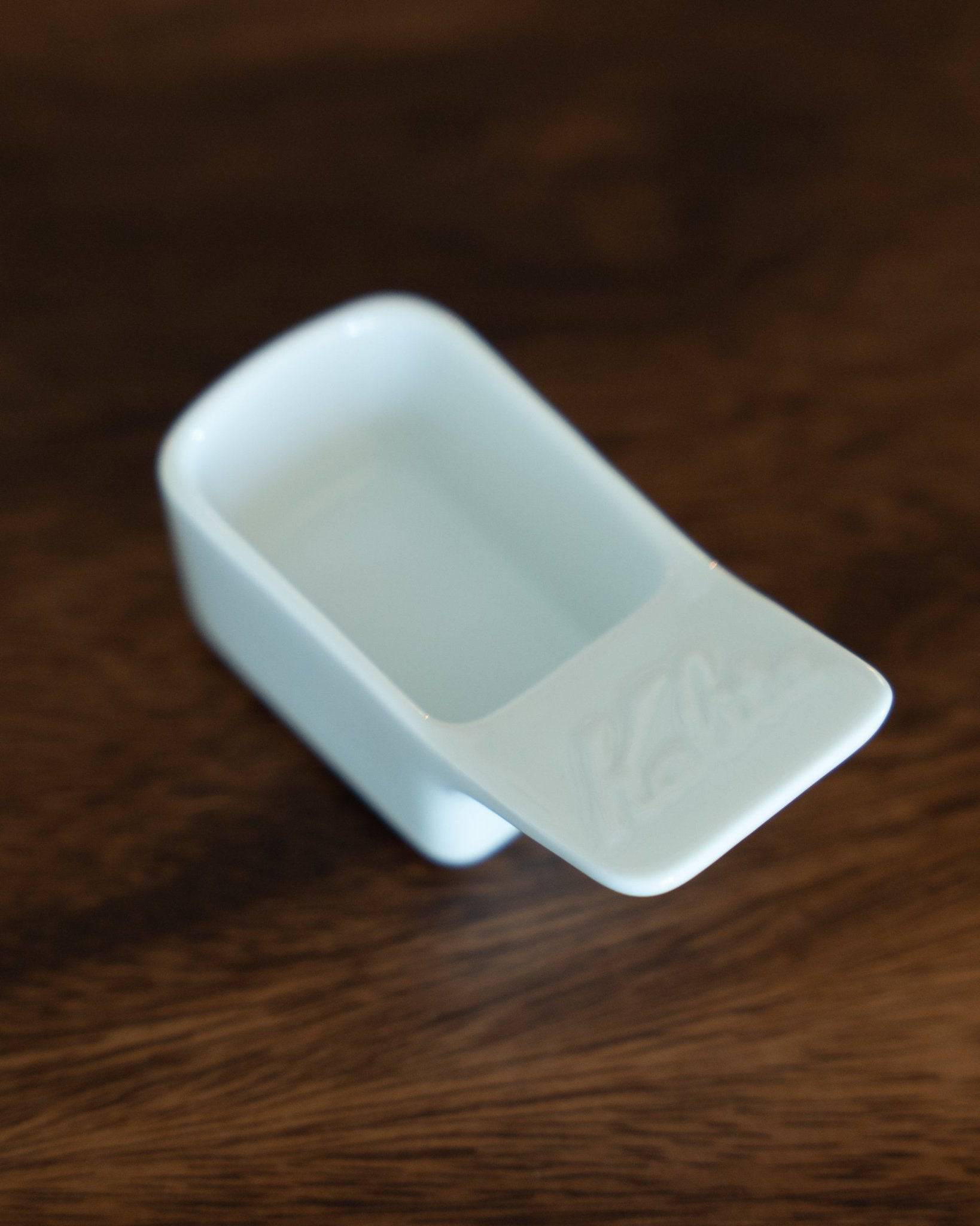 Kalita Hasami-yaki ceramic coffee scoop, 10g capacity, white porcelain with sleek design on wooden surface, precision measuring tool for coffee enthusiasts