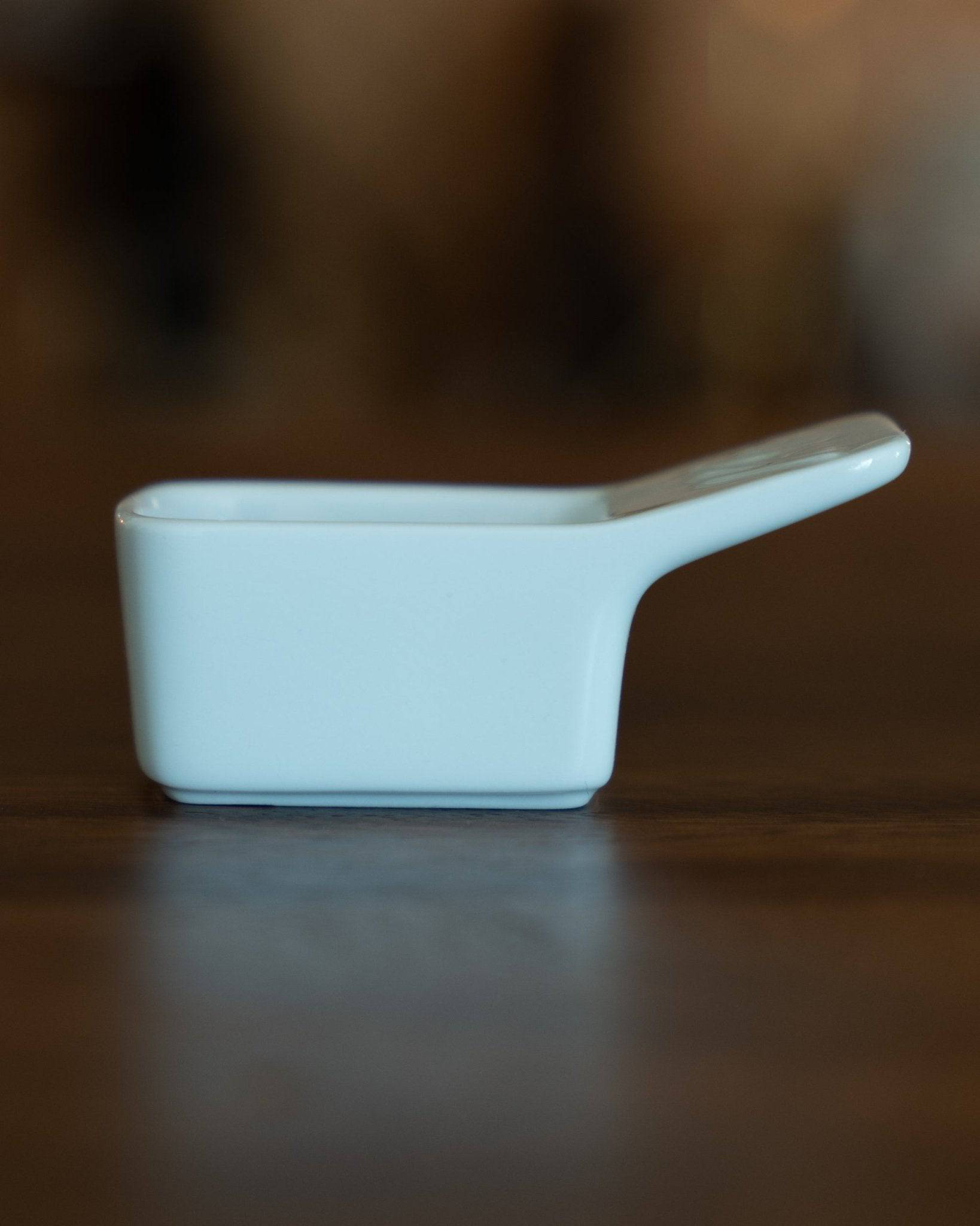 Kalita Hasami-yaki ceramic coffee scoop, 10g capacity, light blue color, sleek design with handle, placed on wooden surface, Japanese craftsmanship
