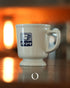 Vintage Kalita coffee mug with blue logo, white ceramic, retro design, on reflective surface with warm orange background lighting, showcasing Showa era Japanese aesthetic