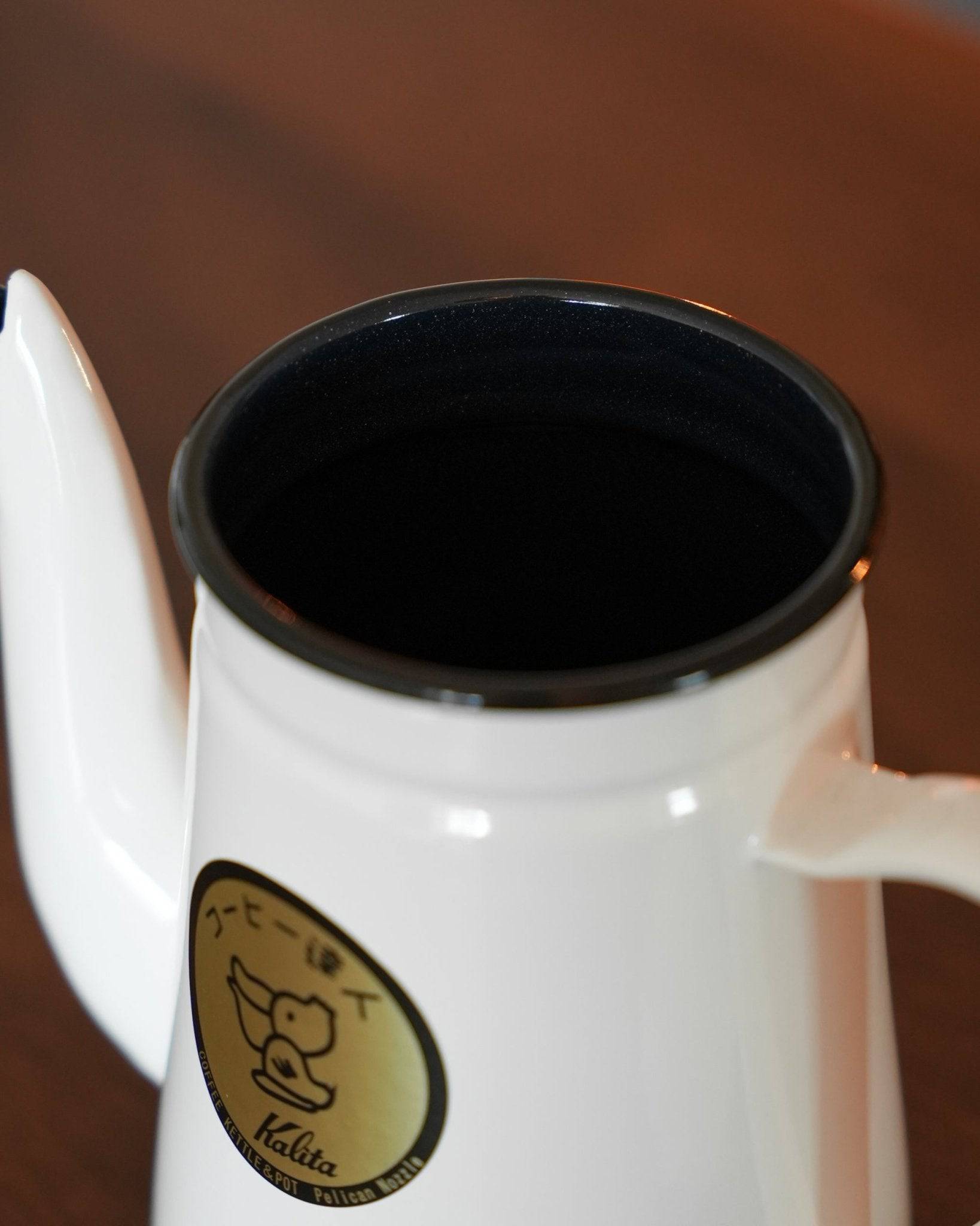 Kalita enamel gooseneck kettle in white, 1L capacity, with distinctive spout and gold brand logo, ideal for precise pour-over coffee brewing