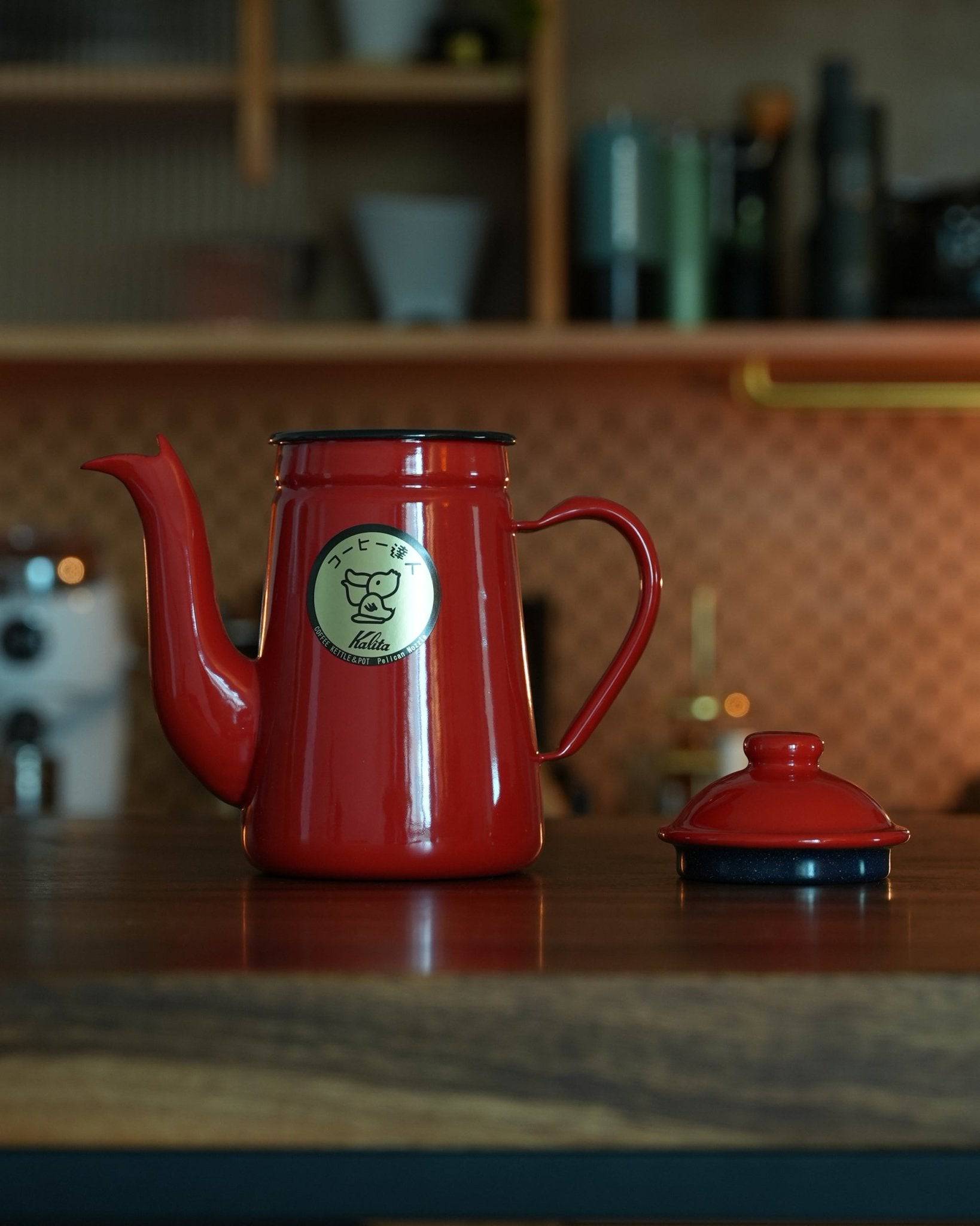Kalita red enamel pour-over kettle with gooseneck spout and lid on kitchen counter, showcasing elegant design and high-quality craftsmanship for precise coffee brewing