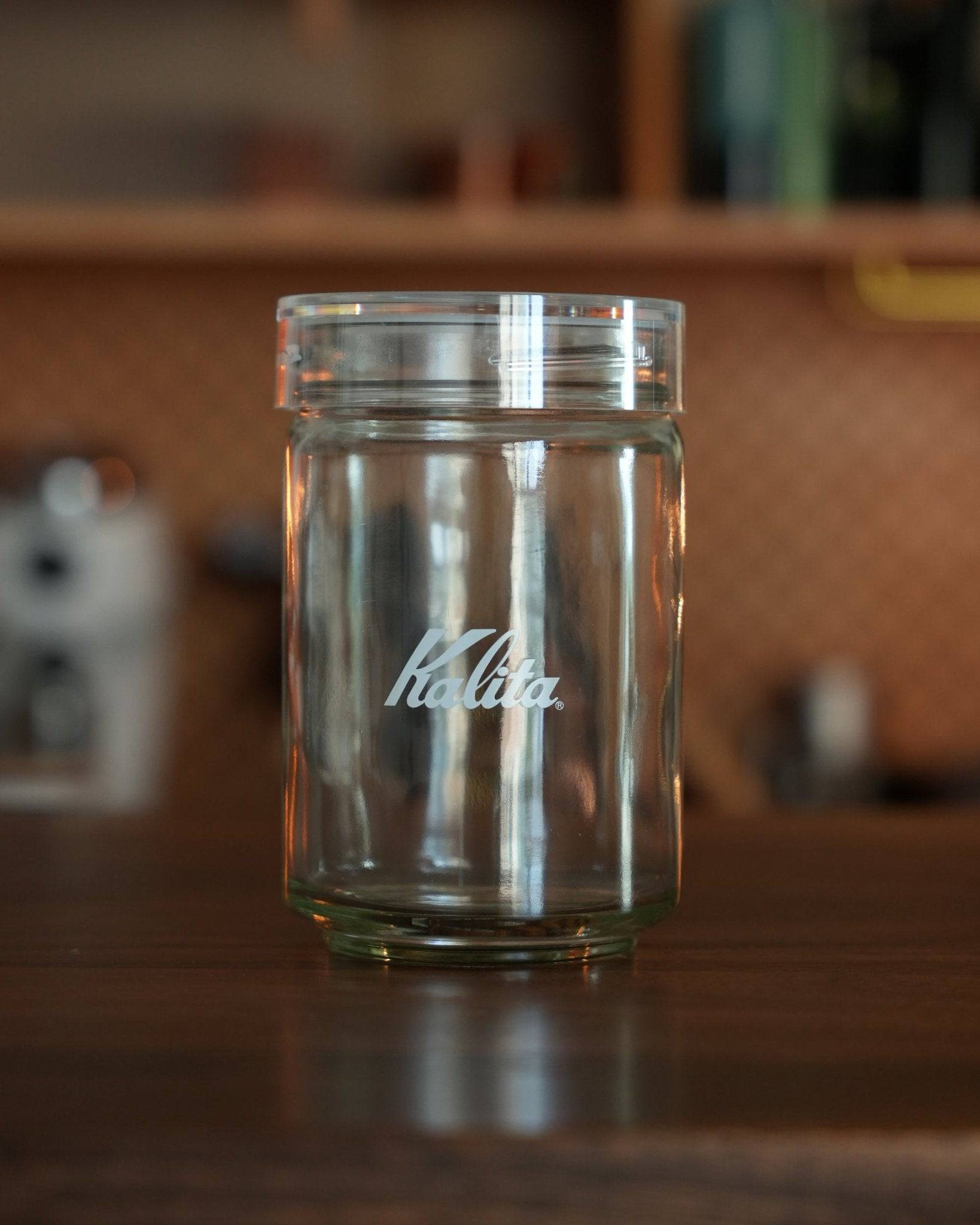 Kalita glass coffee storage jar with airtight lid, 300g capacity, transparent design with brand logo, on wooden surface in kitchen setting