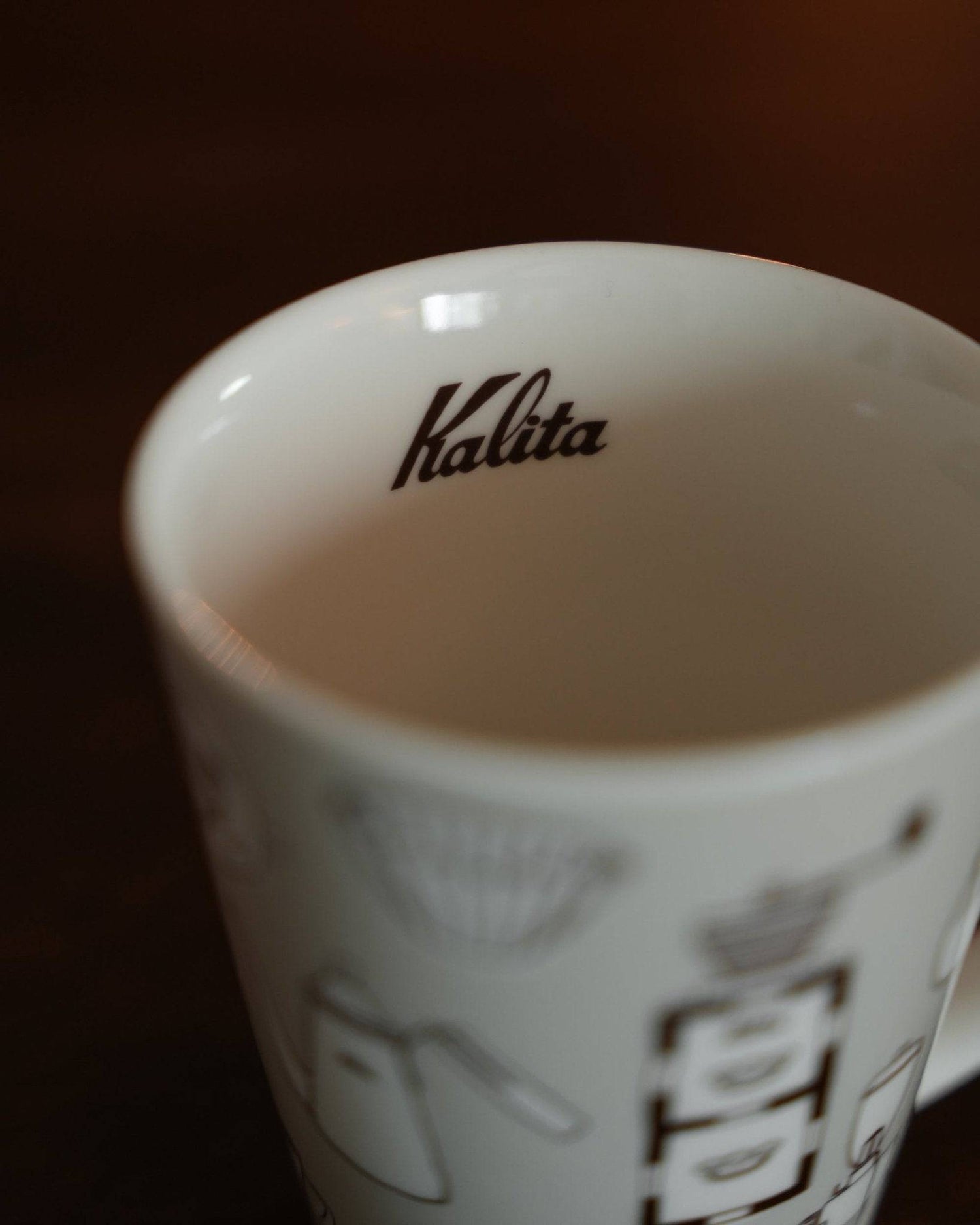 Kalita ceramic mug in warm gray, featuring brand logo inside and coffee equipment illustrations on exterior, showcasing elegant design and craftsmanship