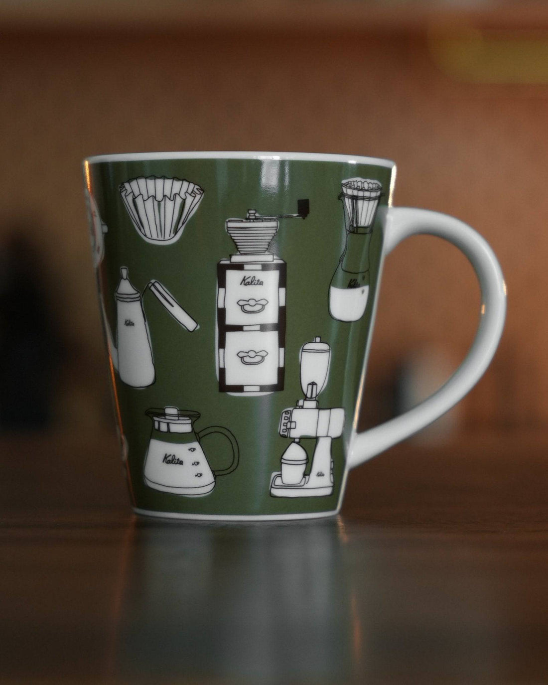 Kalita ceramic mug with green background featuring white illustrations of coffee equipment including grinder, kettle, filters, and brewing devices