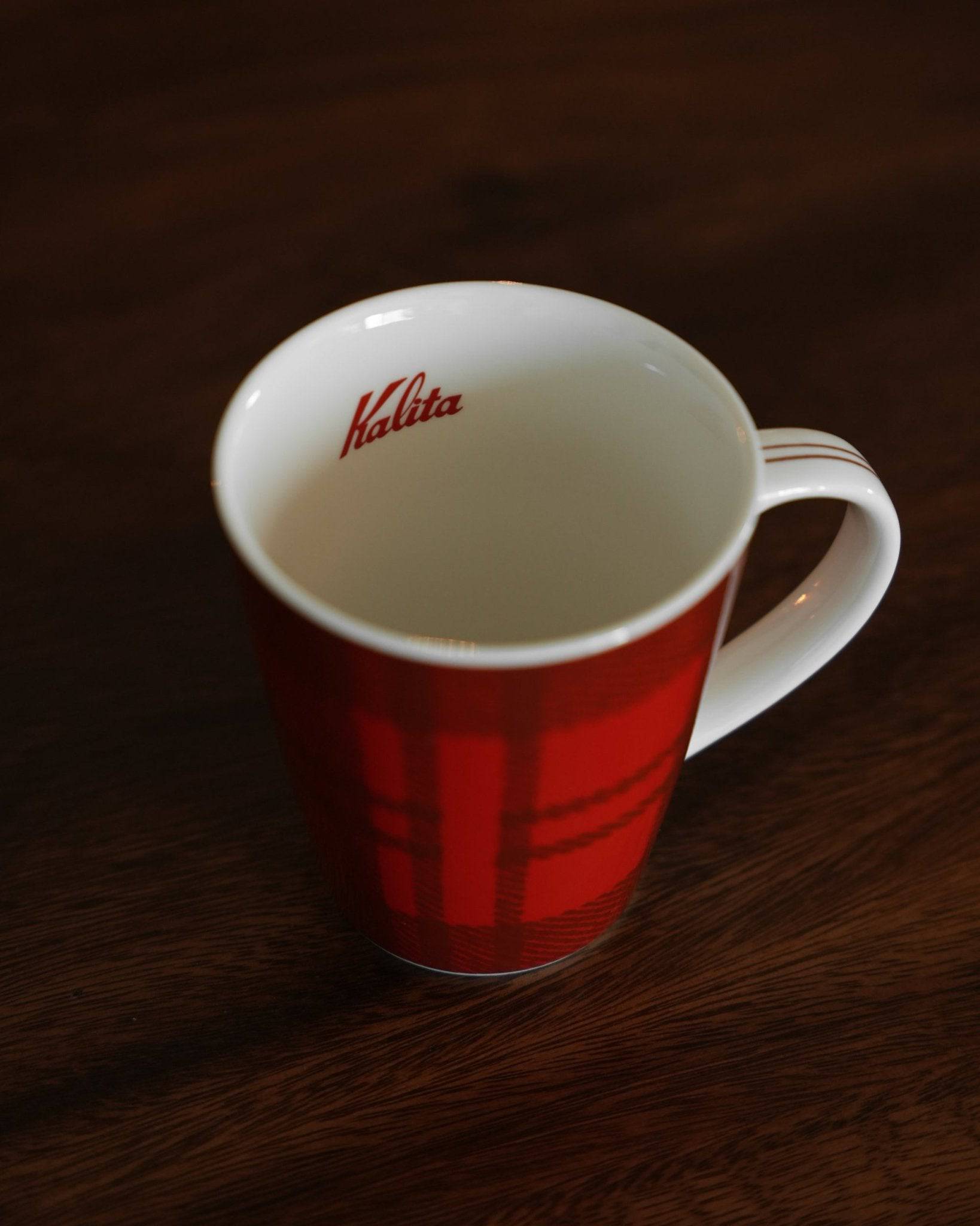 Red Kalita ceramic mug with checkered pattern on wooden surface, showcasing brand logo inside and sleek design, perfect for coffee enthusiasts