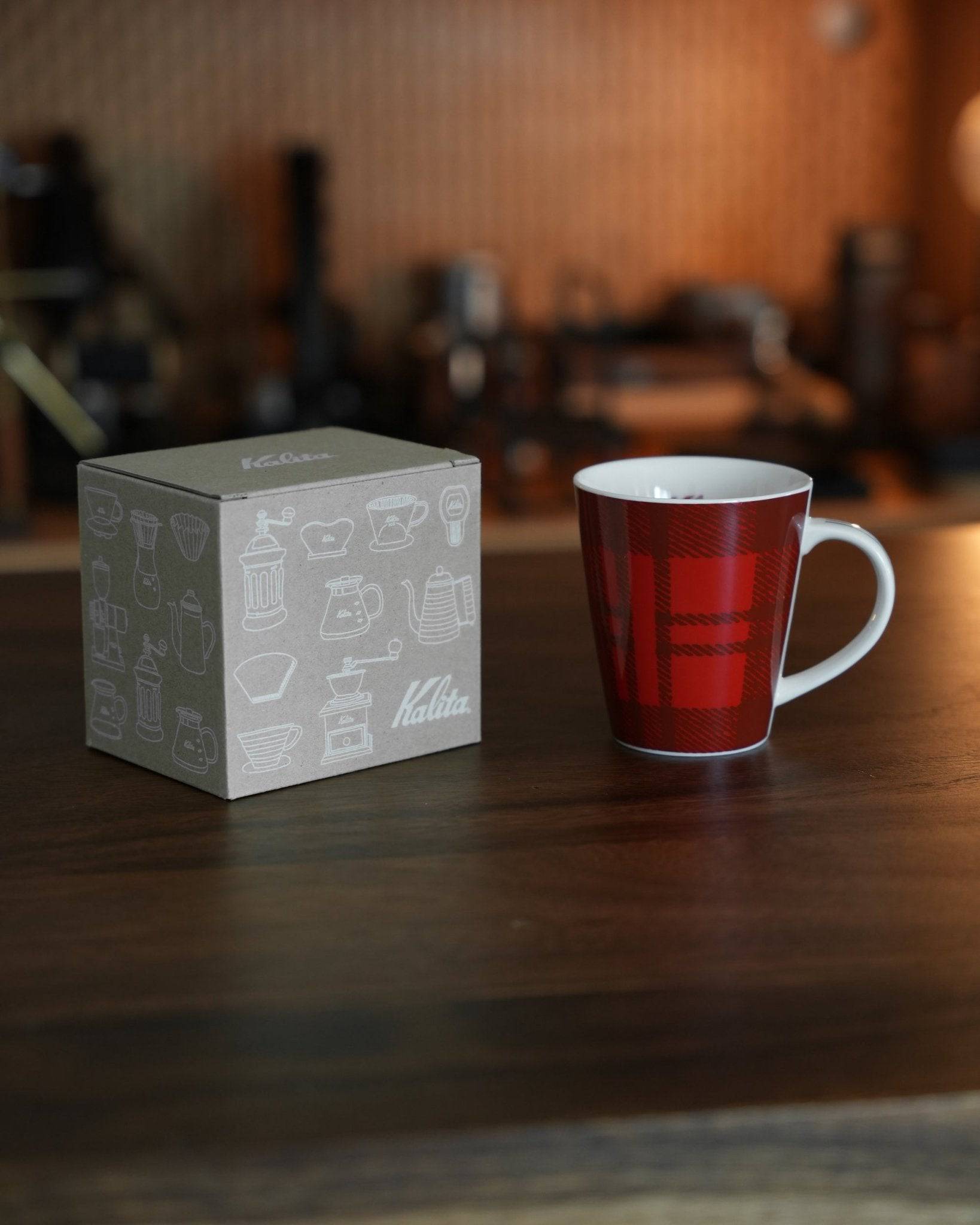 Kalita red plaid ceramic mug with packaging box on wooden counter, coffee equipment in background