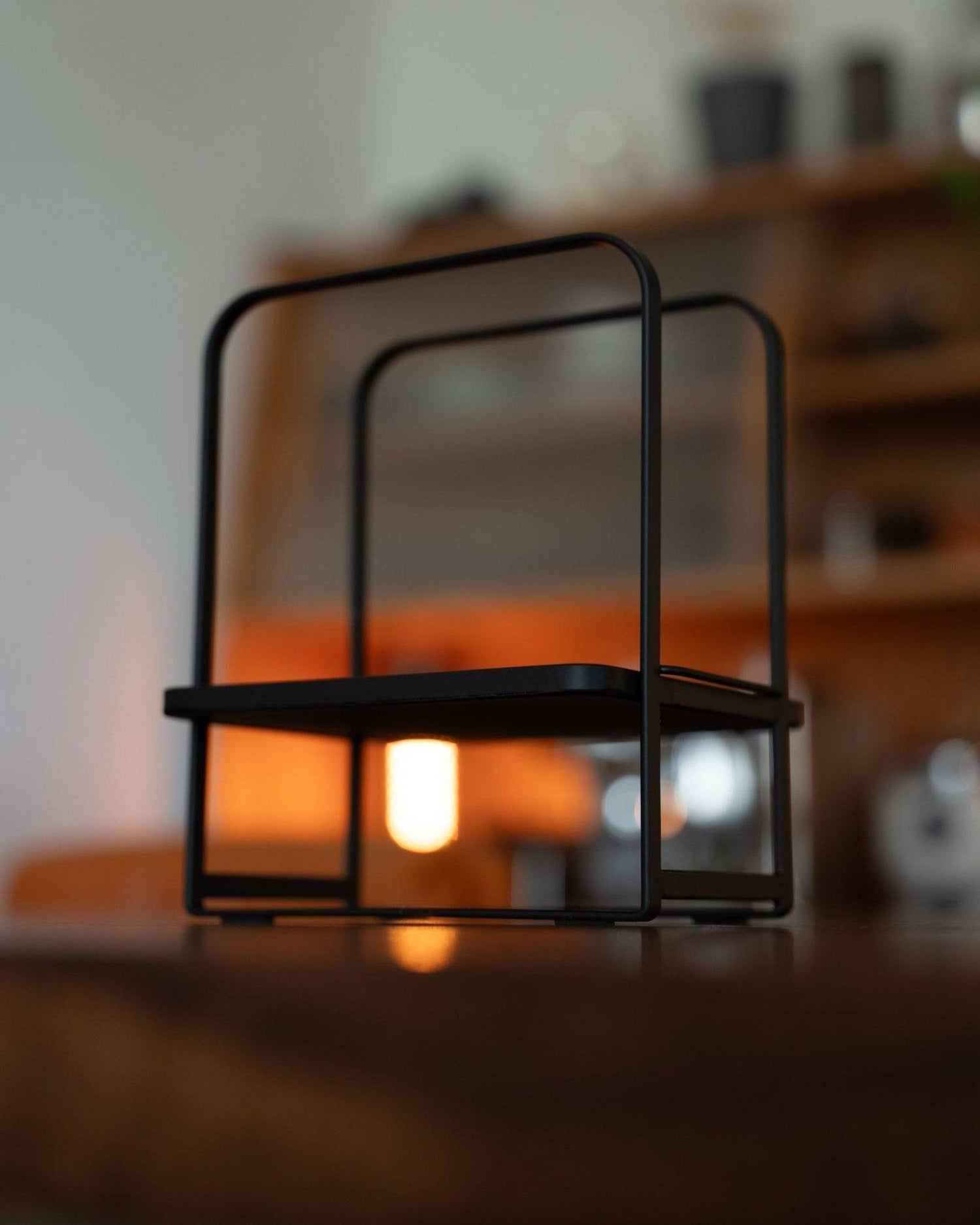 Kalita adjustable coffee dripper stand with black metal frame, illuminated by warm light, on wooden surface in stylish kitchen setting