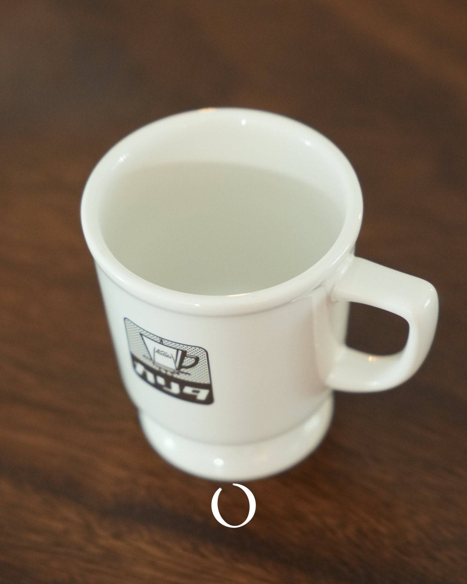 Vintage Kalita ceramic coffee mug with retro logo, white color, wide rim, thick body, sitting on wooden surface, showcasing classic Showa era design for authentic Japanese coffee experience
