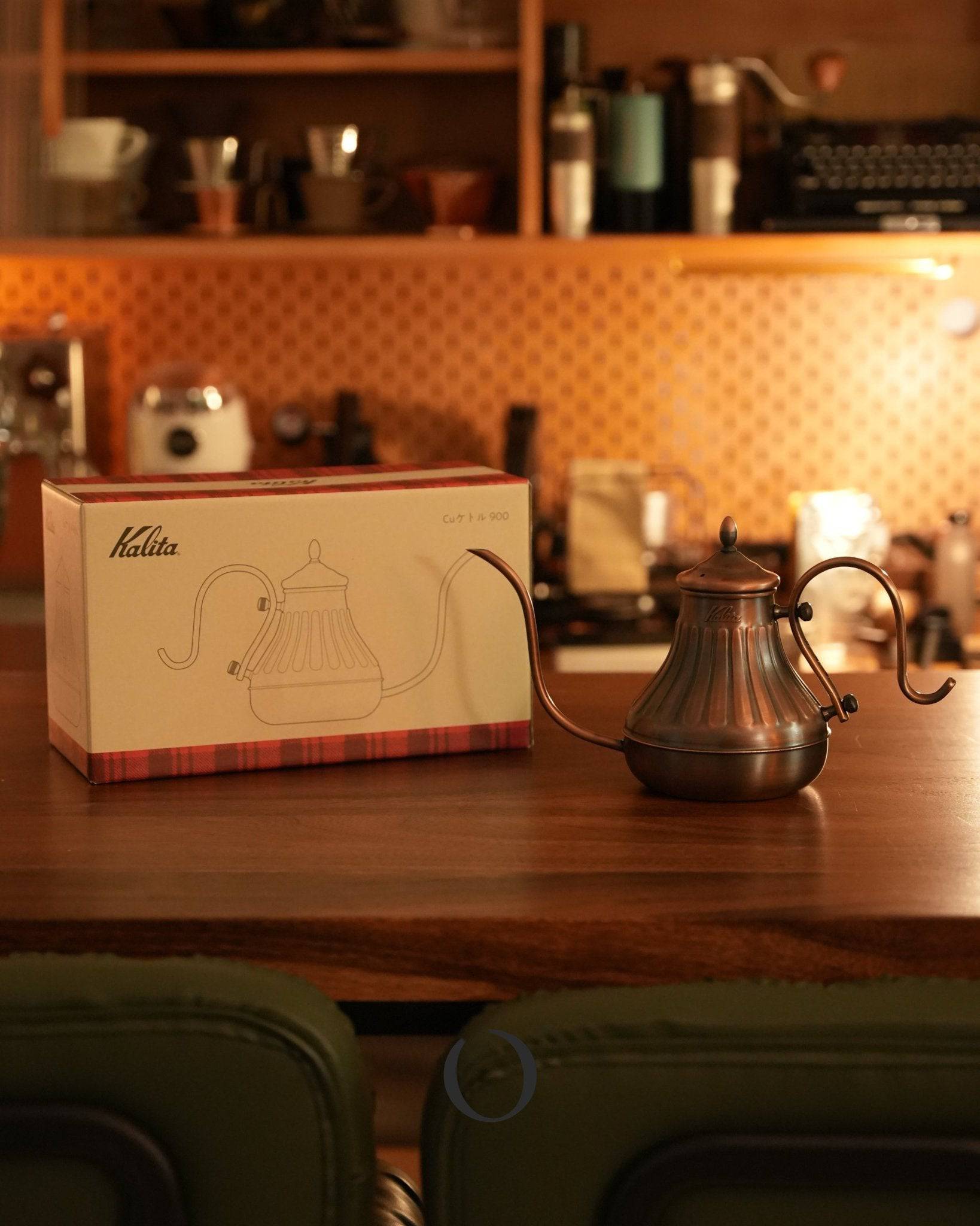 Kalita copper pour-over kettle with box on wooden countertop in cozy kitchen, warm lighting, vintage-style appliances in background